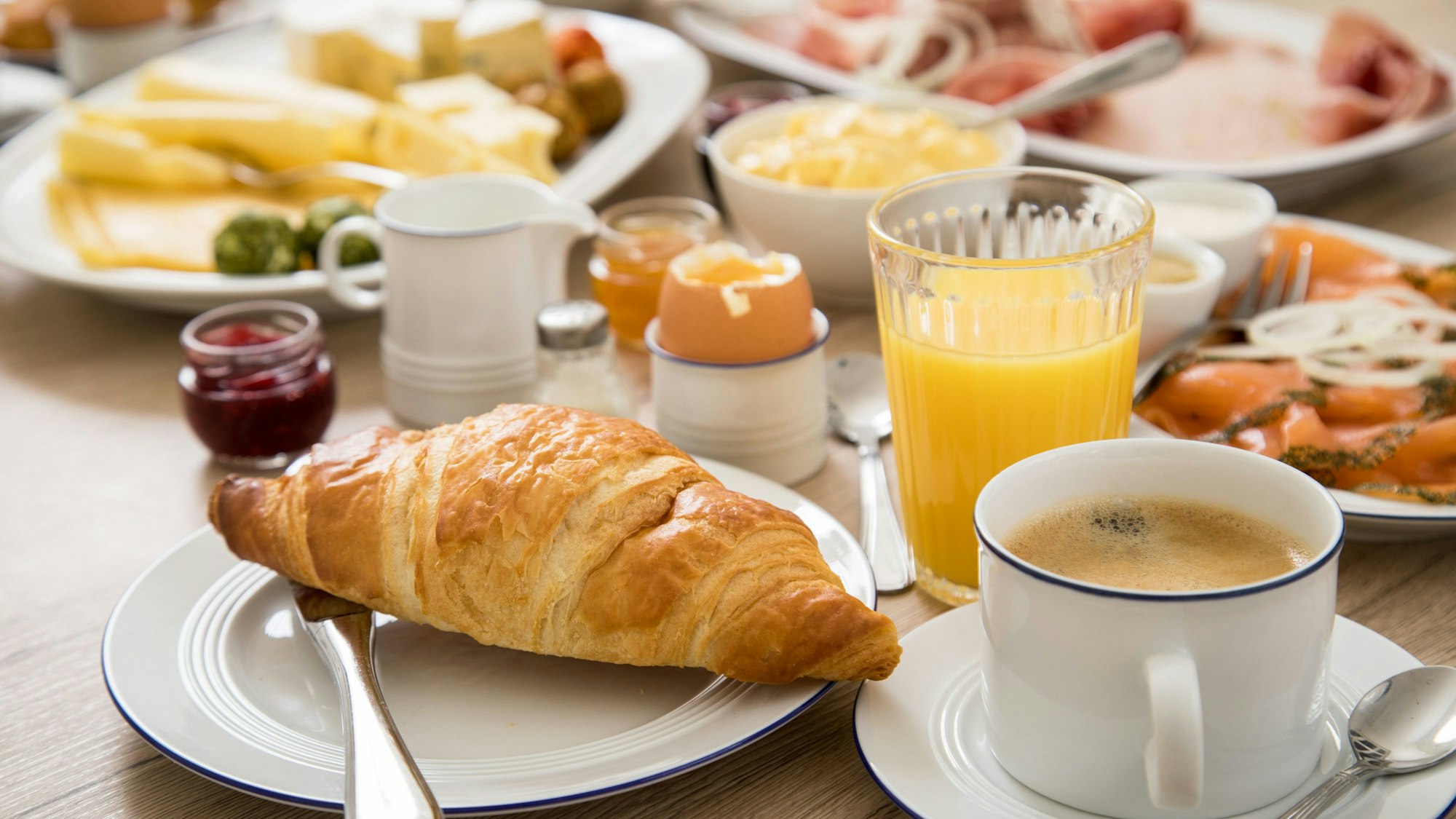Ein Frühstückstisch mit Kaffee, Orangensaft, einem hartgekochten Ei und verschiedenem Aufschnitt. (Symbolbild)