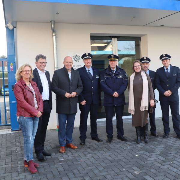 Frauen, Männer und Polizisten stehen vor einem Gebäude.