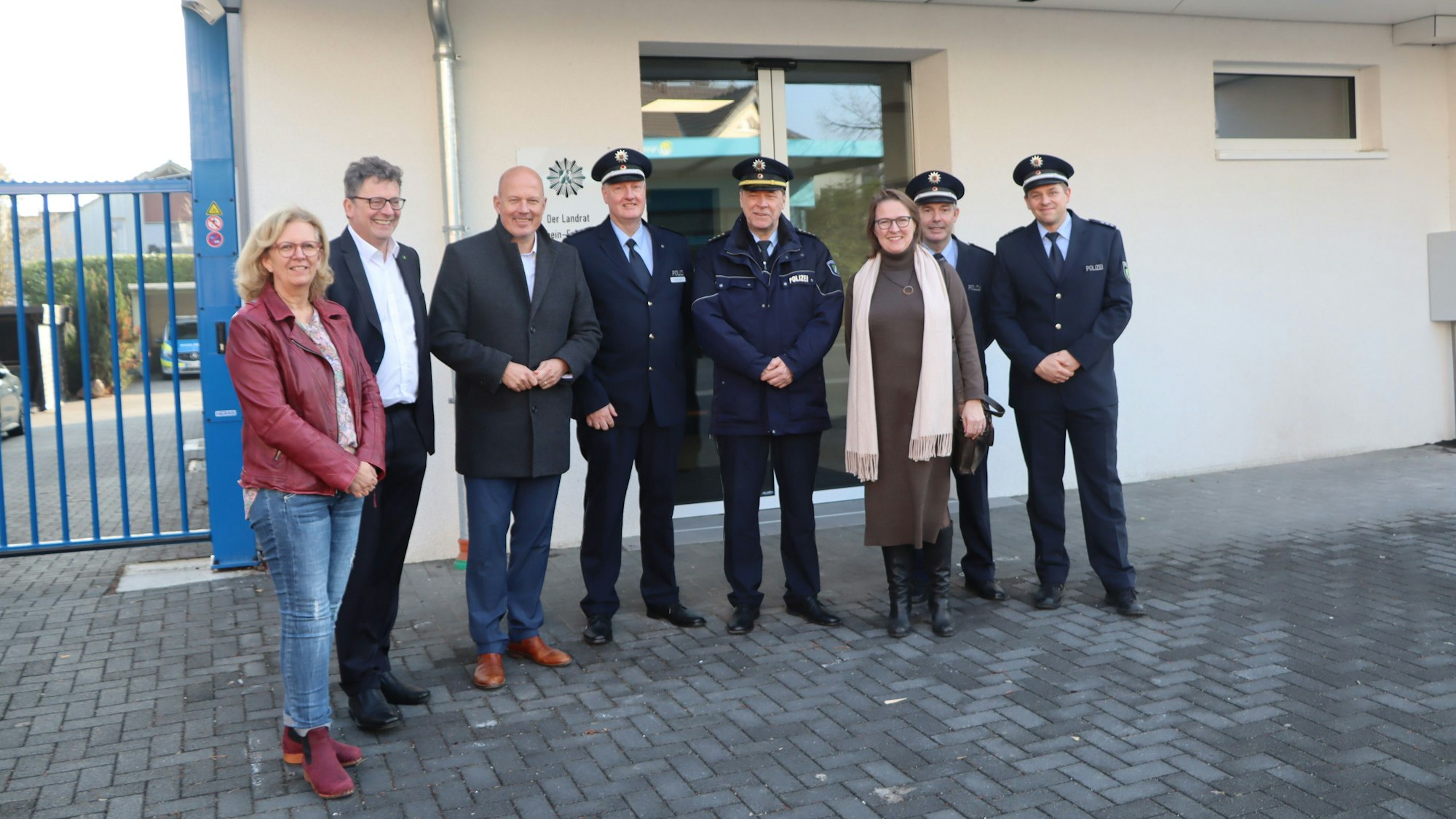 Frauen, Männer und Polizisten stehen vor einem Gebäude.