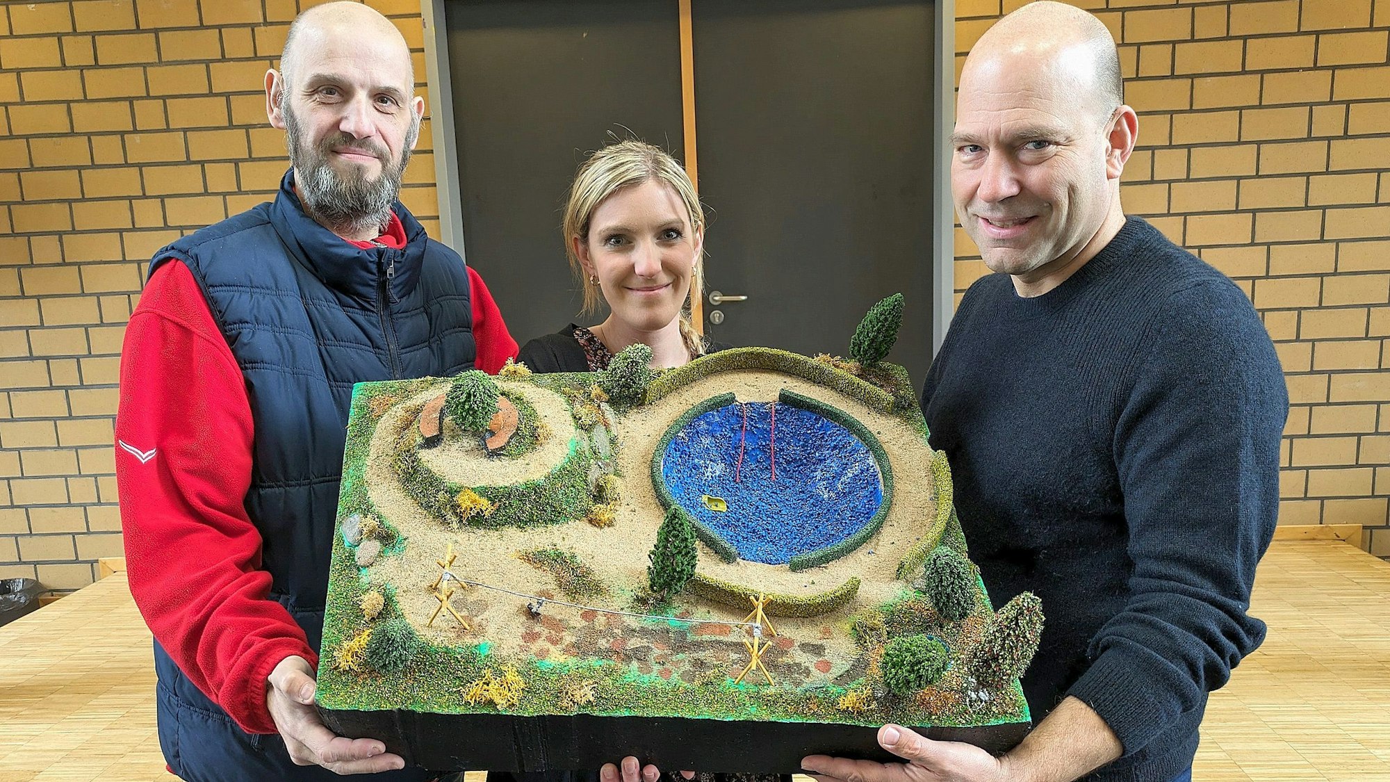 Christoph Nagel und Sarah Rösgen vom Förderverein sowie Schulleiter André Decker (r.) haben ein Modell des neuen Pausenhofes in der Hand.
