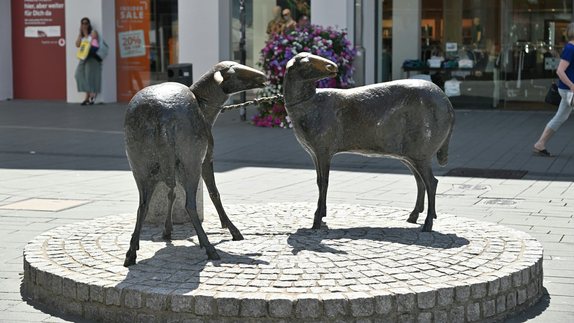 Fußgänger laufen an Statue von Schafen in der Gladbacher Fußgängerzone vorbei.