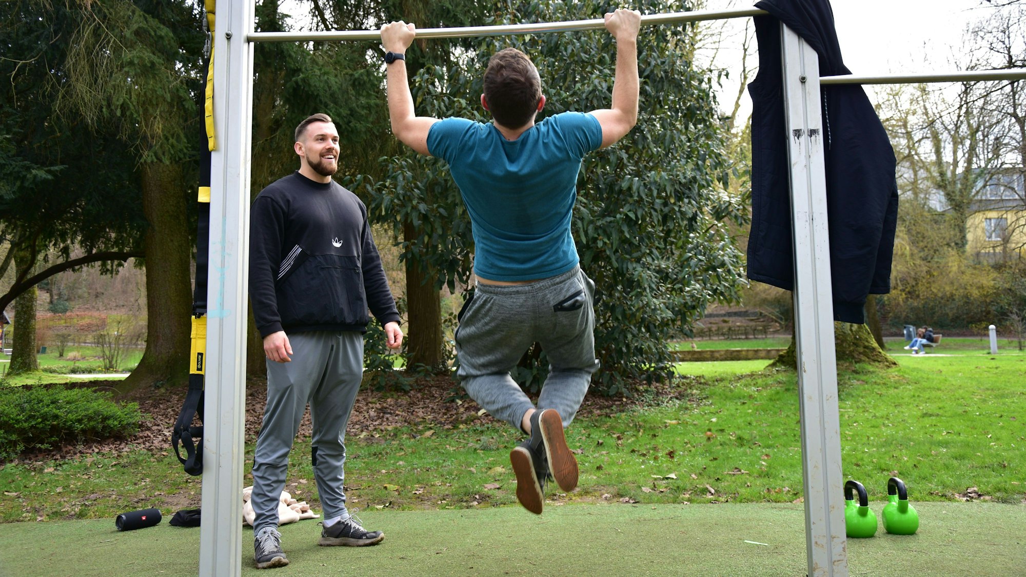 Im Kurpark Hennef trainieren zwei Männer bei einer Trimm-Dich-Anlage.