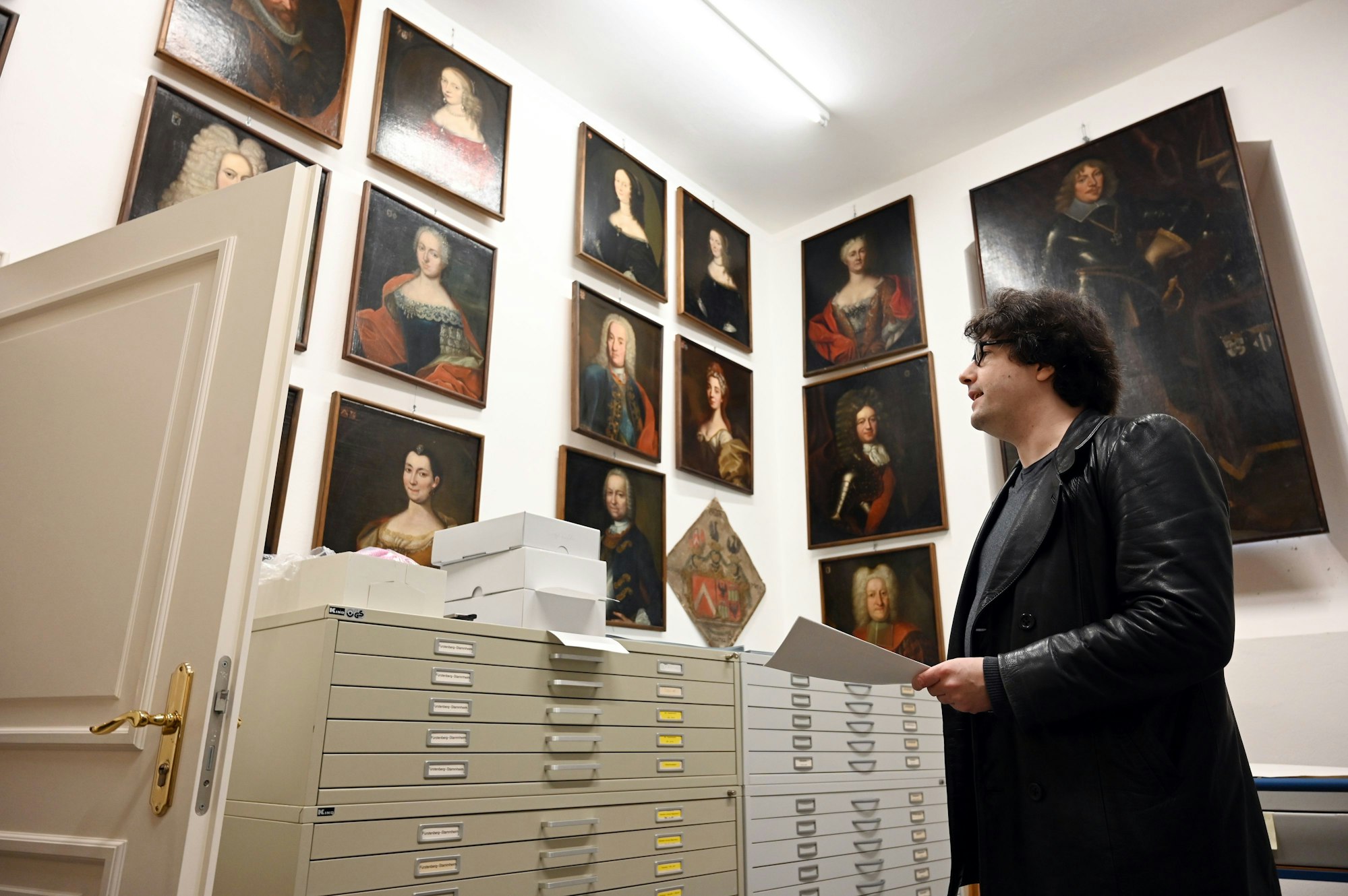 Juliano de Assis Mendonça schaut auf Bilder der Ahnengalerie der Freiherren von dem Bongart, die im Depot der Vereinigten Adelsarchive im Rheinland zu sehen sind.