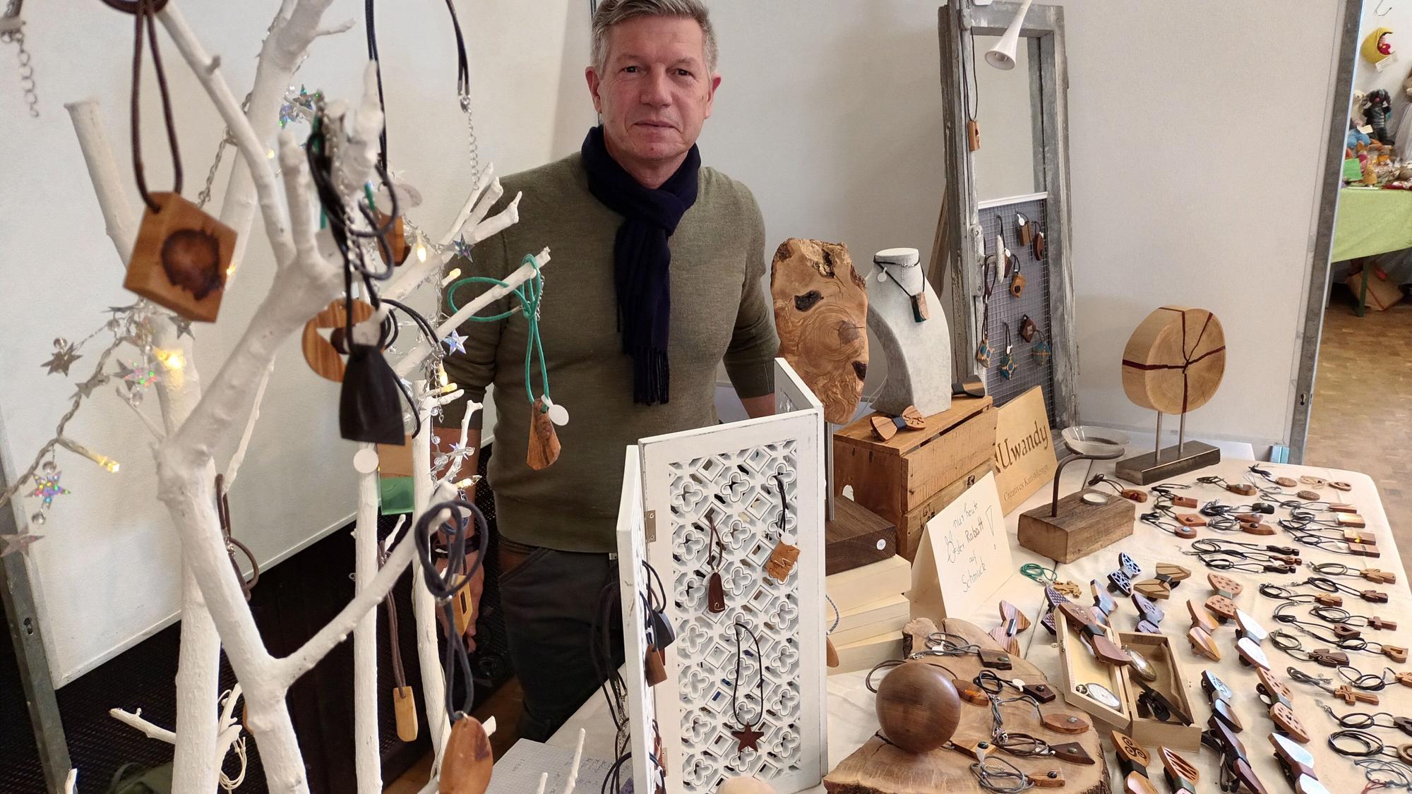 Ein Mann an einem Stand mit Holzschmuck und Skulpturen