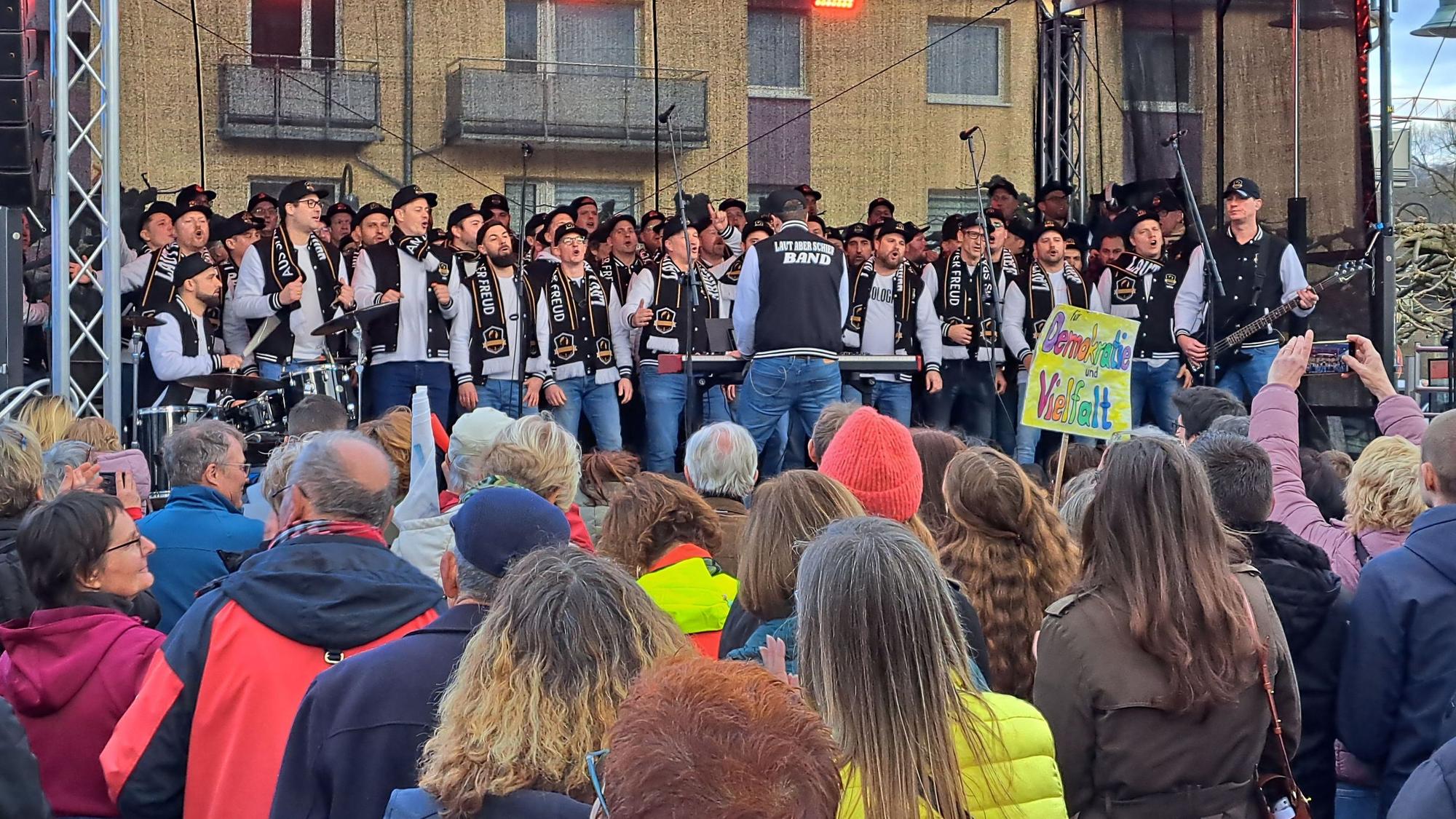 Der Marialindener Männerchor „Laut aber schief“ steht auf einer Bühne bei einer Demonstration auf dem Overather Bahnhofplatz.