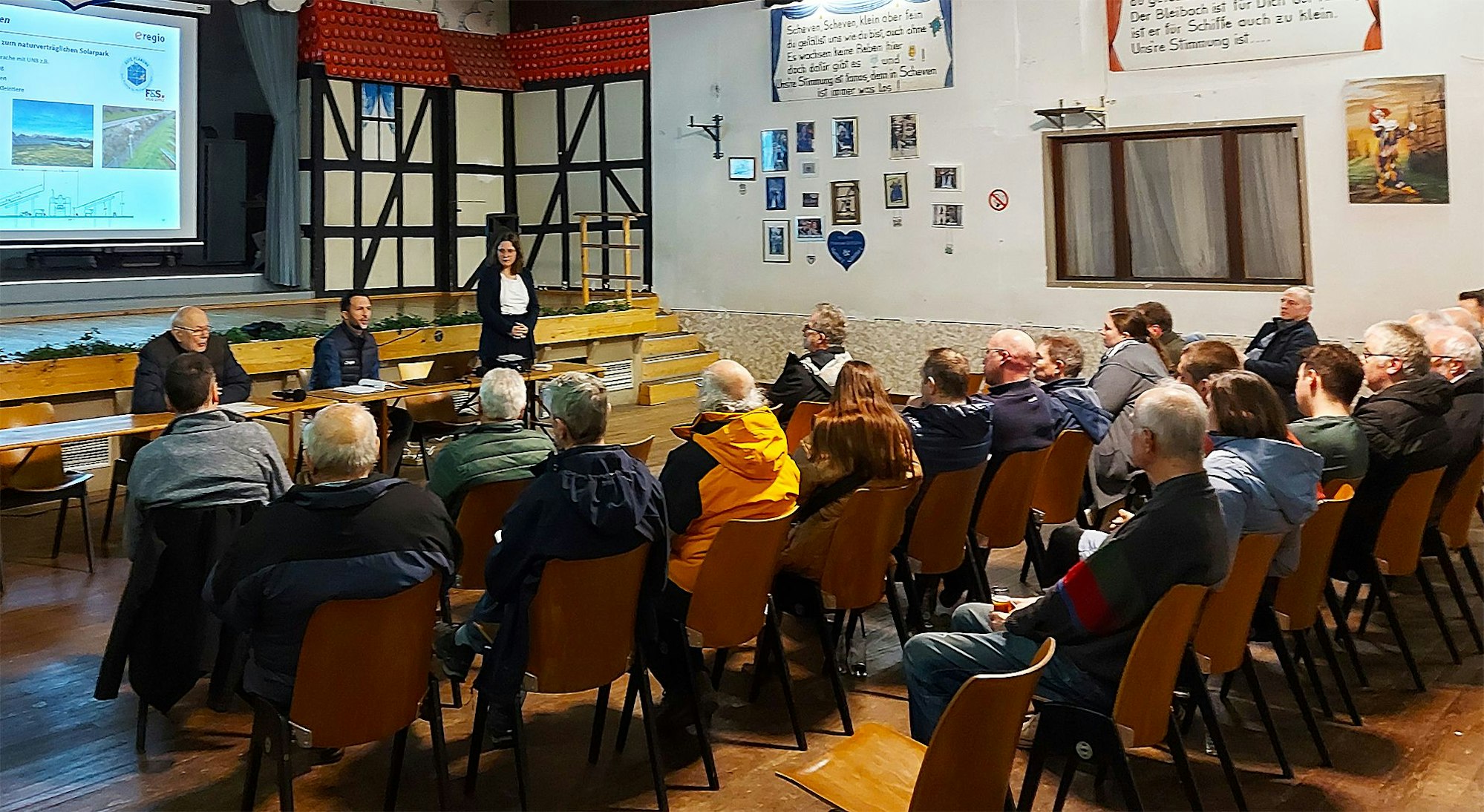 In mehreren Stuhlreihen sitzen interessierte Bürger, vorne stellt ein e-regio-Vertreter die Pläne vor.
