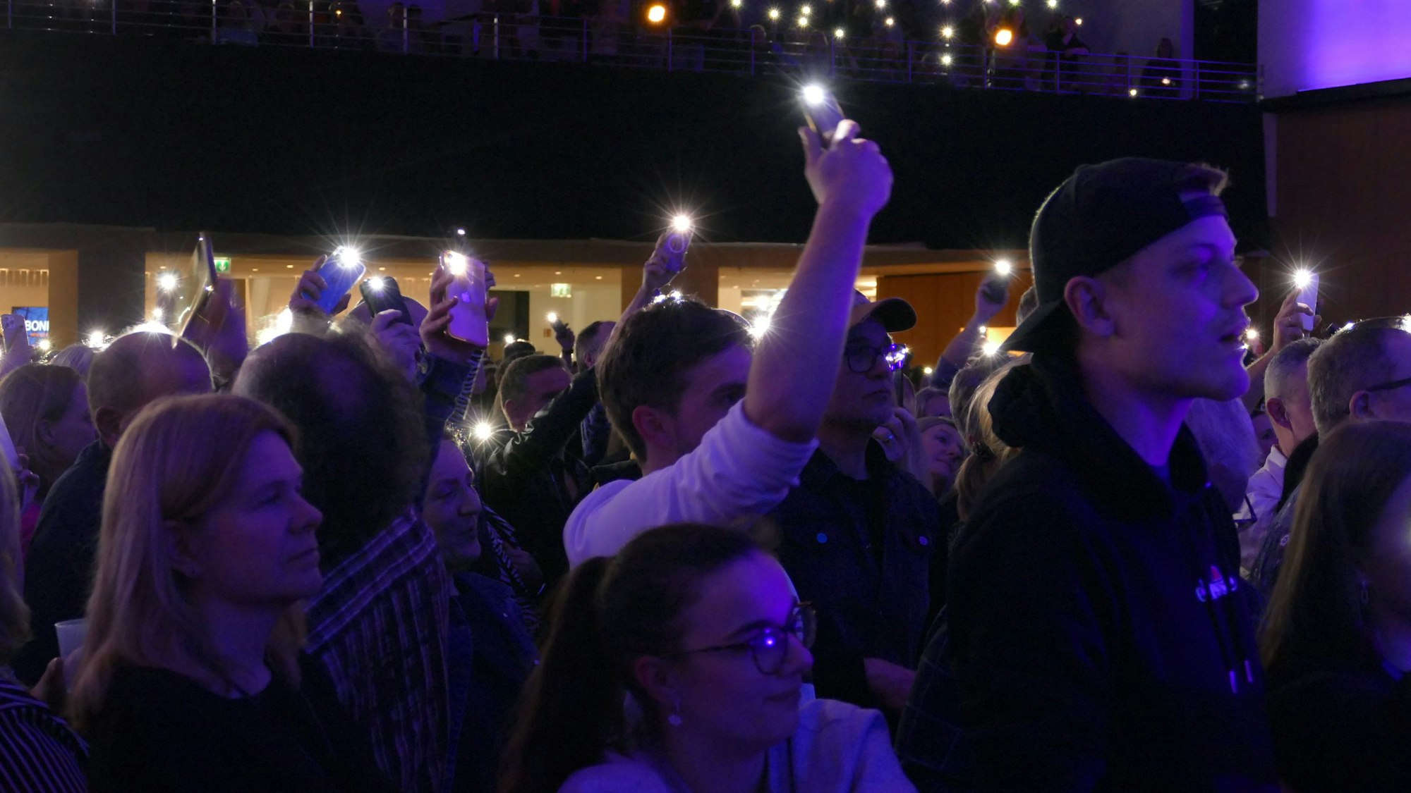 Menschen halten ihre Smartphones mit Taschenrampenfunktion in die Höhe.