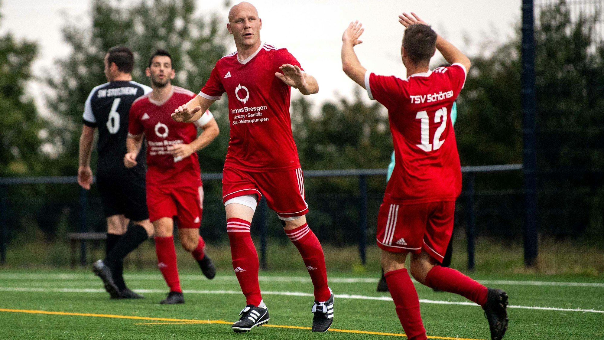 Das Bild zeigt Sven Gräbe, wie er mit einem Teamkollegen abklatscht.