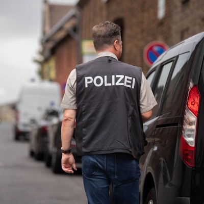 Nach einem brutalen Überfall in Zülpich-Füssenich geht ein Ermittler, der eine Weste mit der Aufschrift „Polizei“ trägt, zu einem Haus.