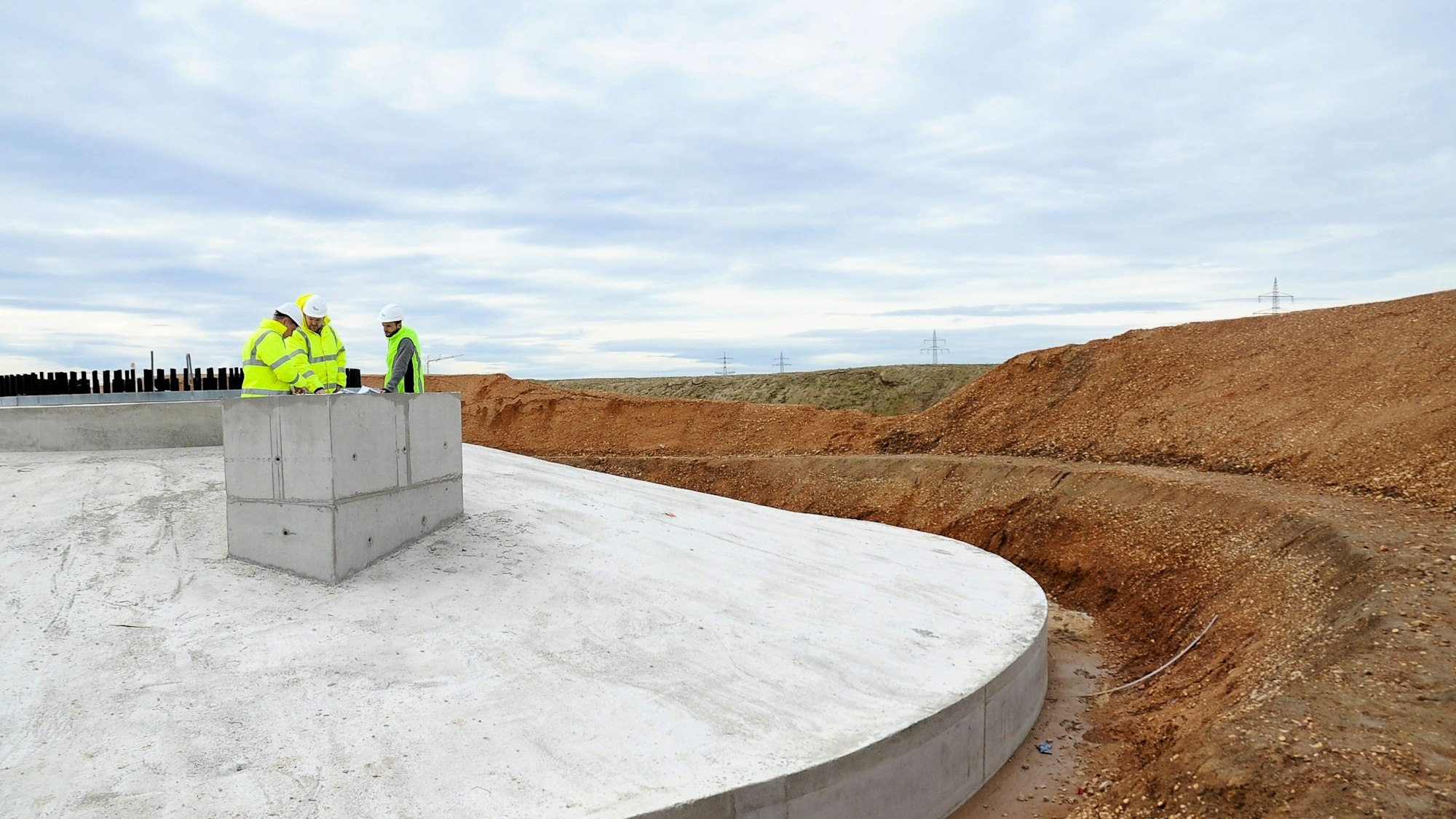 In Erftstadt-Friesheim stehen drei Menschen auf dem Fundament einer Windkraftanlage. Die REA GmbH baut in Friesheim den Windpark Erftstadt A1. Auf dem Bild Bauleiter Udo Hanisch, Teamleiter Projektentwickler Daniel Rüttgers und Geschäftsführer Klaus Wildrath.