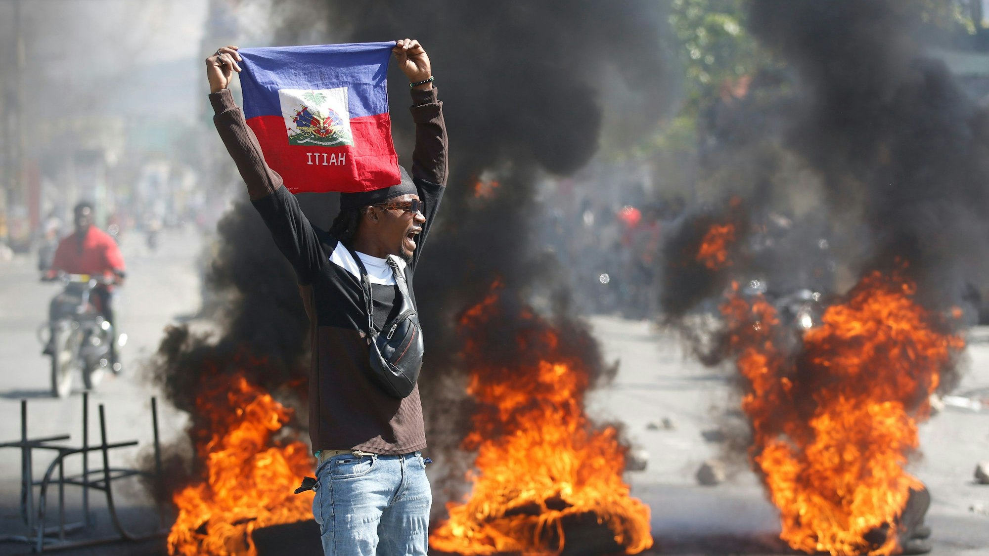 Ein Demonstrant hält eine haitianische Flagge während Protesten für den Rücktritt von Premierminister Henry hoch.