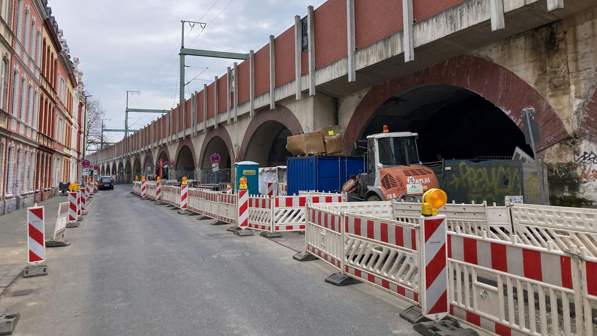 Absperrungen stehen entlang einer Straße am Bahndamm.