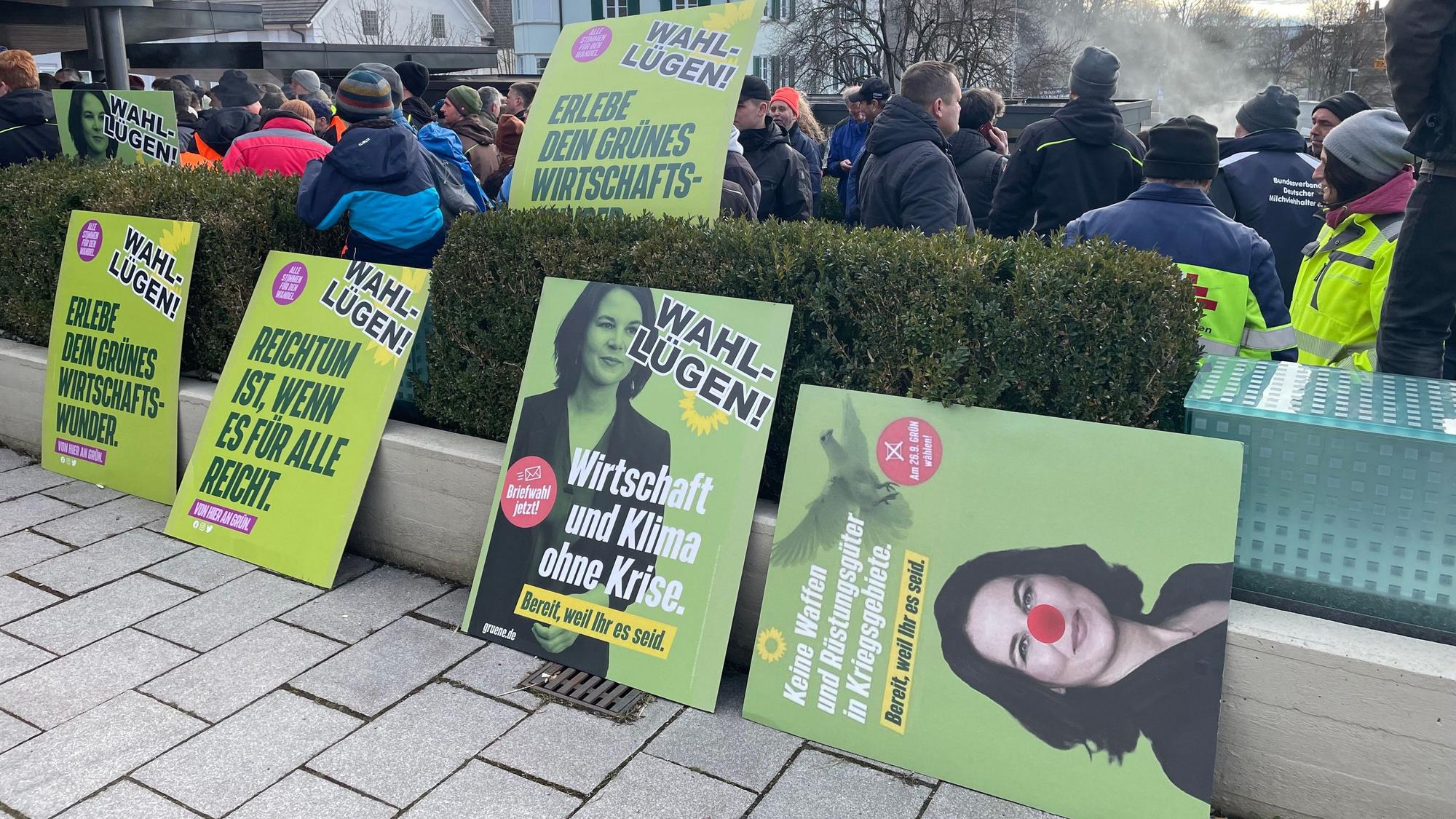 „Für jeden Missstand muss es eine einfache Ursache geben“: Aufgebrachte Landwirte protestieren mit verfremdeten Wahlplakaten beim politischen Aschermittwoch der Grünen in Biberach. Kurz darauf eskaliert die Lage vor der Halle, die Veranstaltung wird abgesagt.