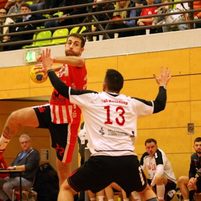 Das Bild zeigt David Henzel beim Sprungwurf. Ein Abwehrspieler versucht zu blocken.