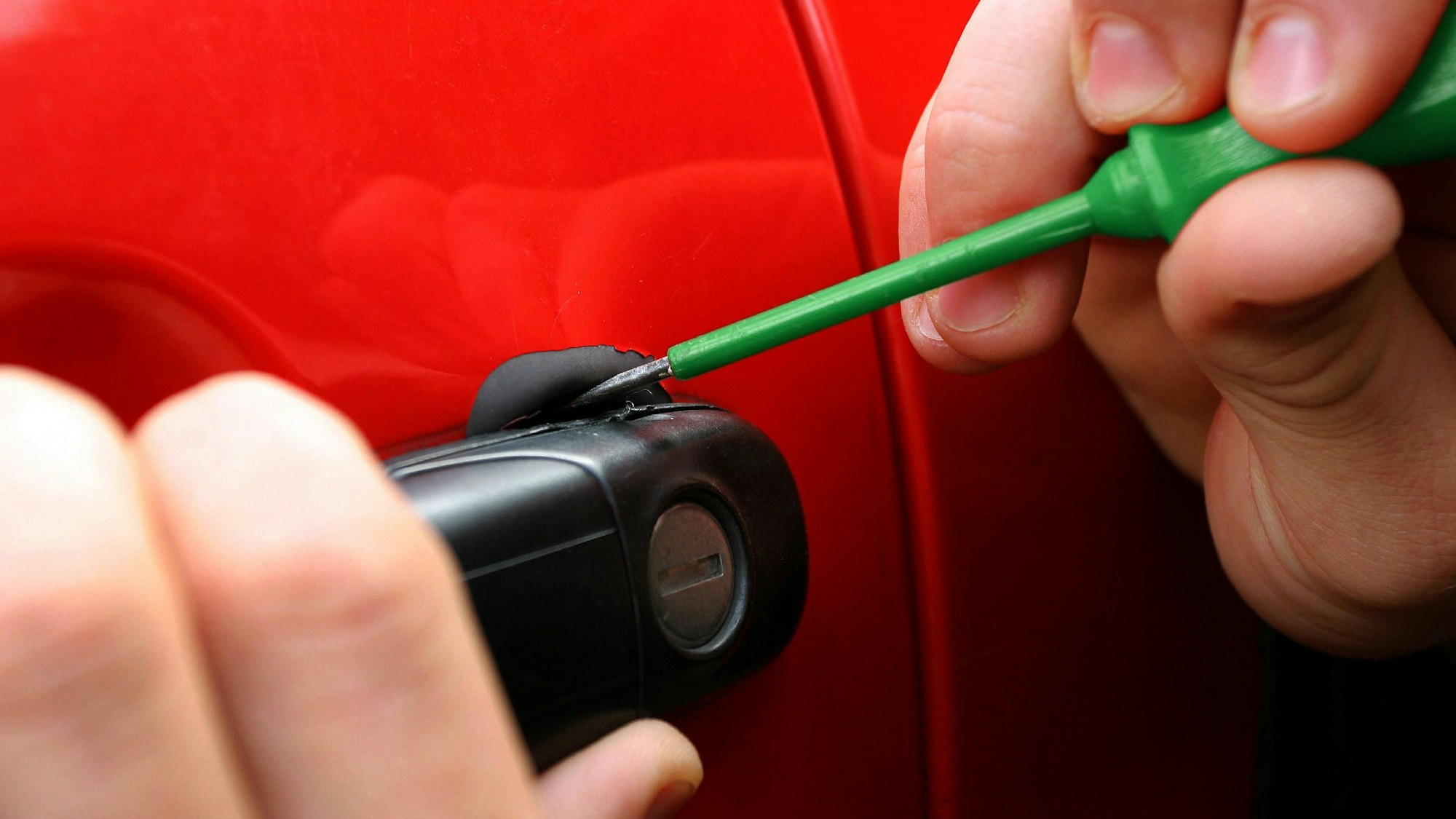 Eine Autotür wird mit Hilfe eines Schraubenziehers geöffnet.