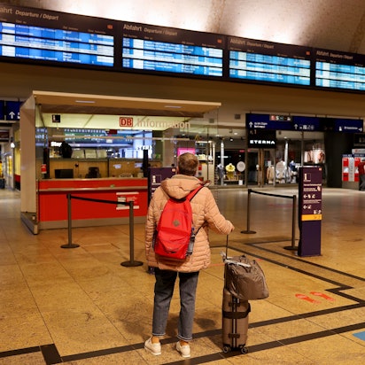 Eine Frau steht vor der Anzeigetafel im Hauptbahnhof Köln.