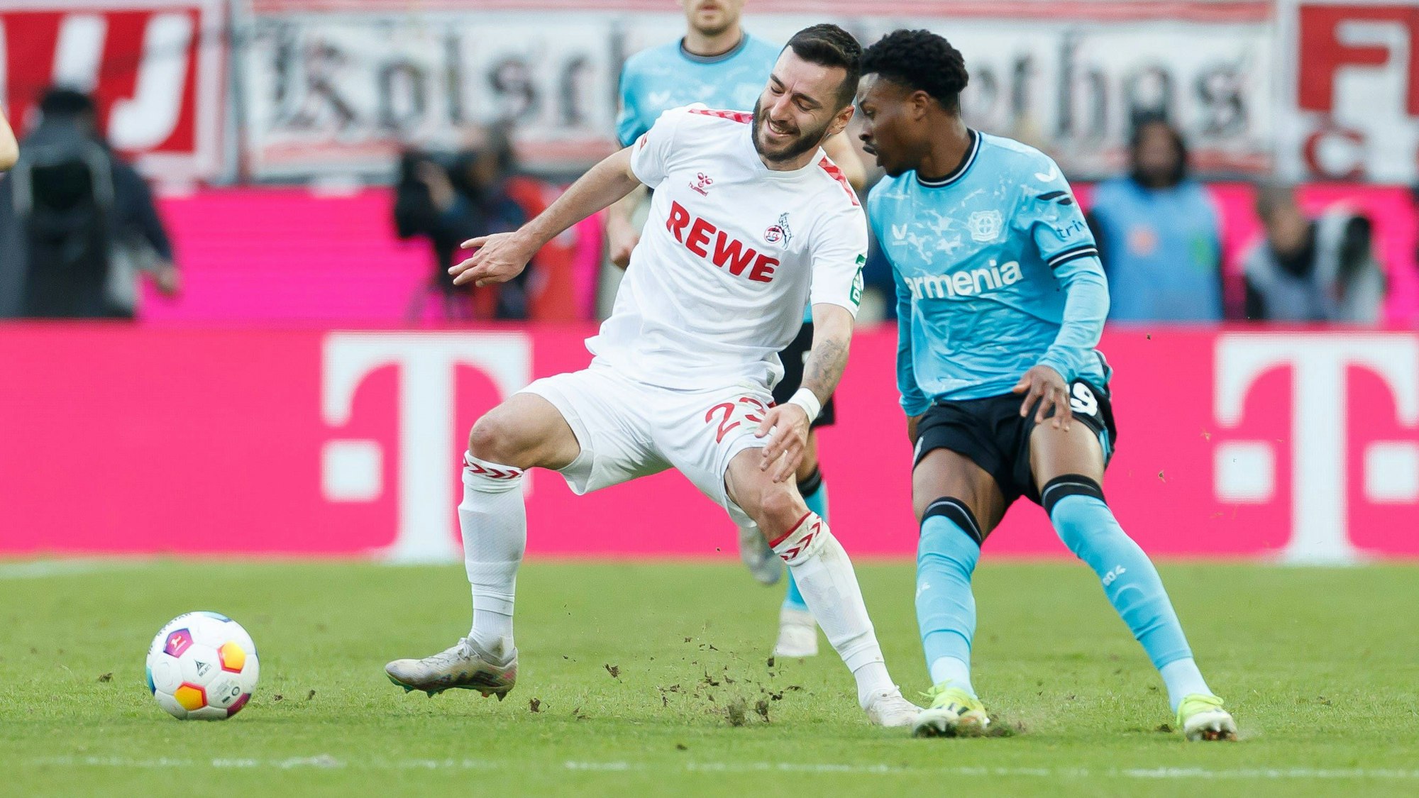 Nicht alles im grünen Bereich: Beim Zweikampf zwischen Kölns Sargis Adamyan und Leverkusens Nathan Tella fliegen die Rasenstücke.