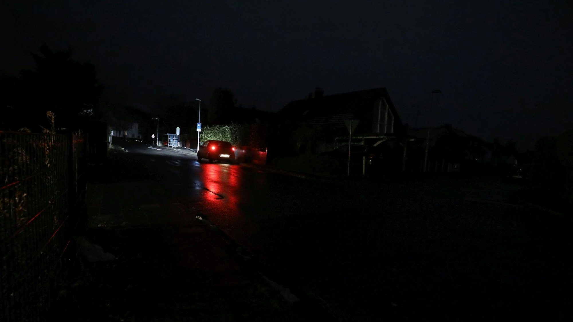 Ein Auto fährt über eine sehr dunkle Straße, die nur durch die Scheinwerfer beleuchtet wird.