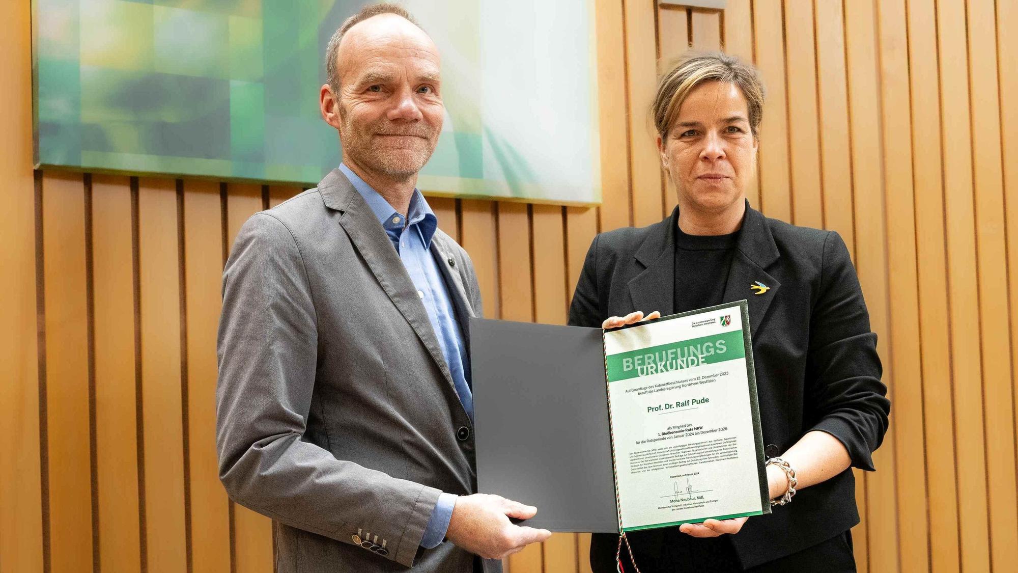 Im Landtag erhält Ralf Pude die Berufungsurkunde von Wirtschafts- und Klimaschutzministerin Mona Neubaur.