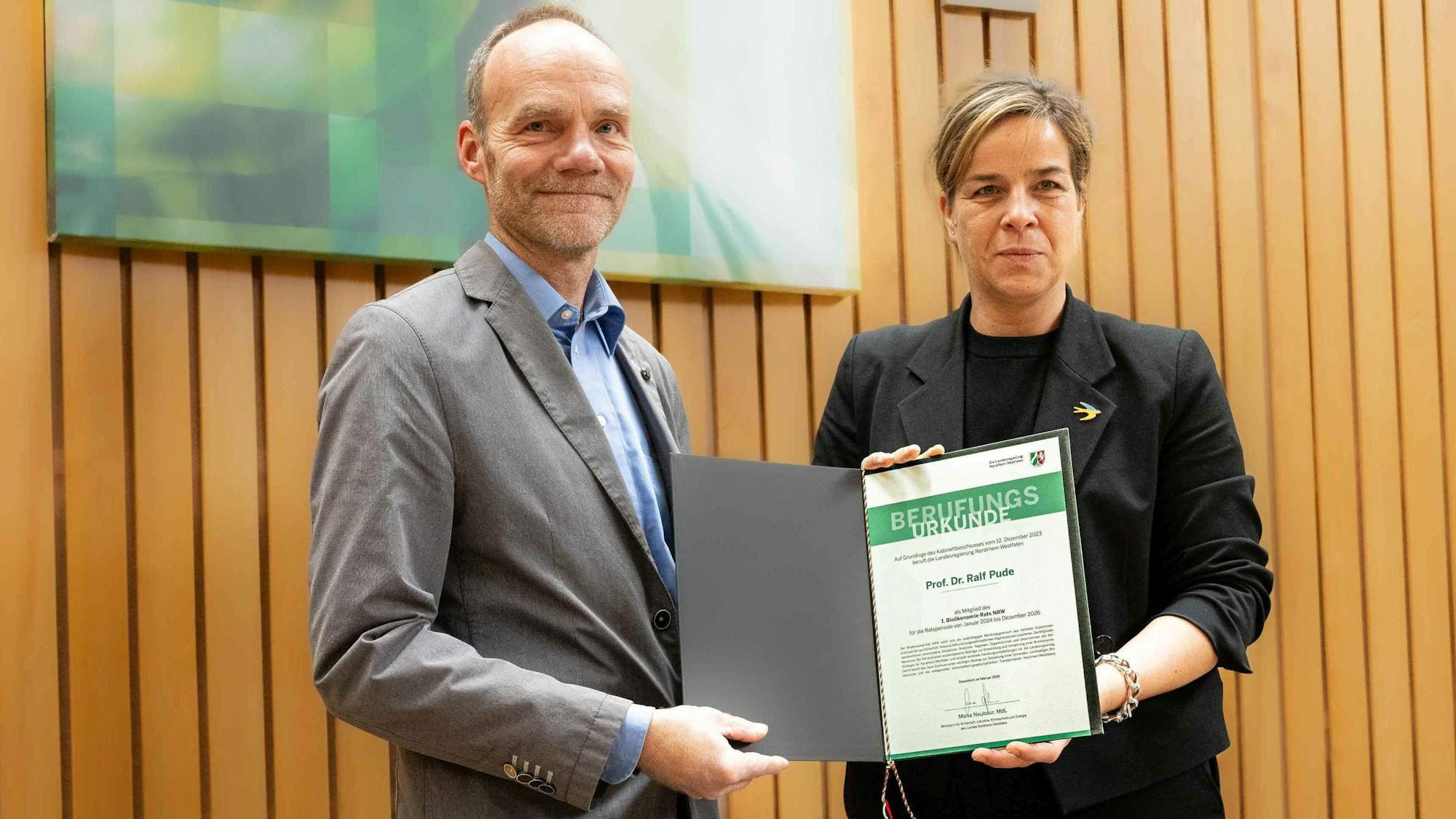 Im Landtag erhält Ralf Pude die Berufungsurkunde von Wirtschafts- und Klimaschutzministerin Mona Neubaur.