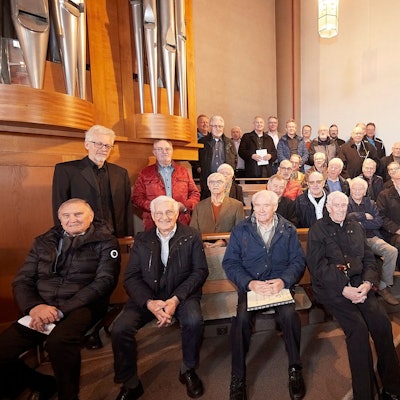 Zahlreiche Sänger von Männergesangvereinen stehen und sitzen an einer Kirchenorgel.
