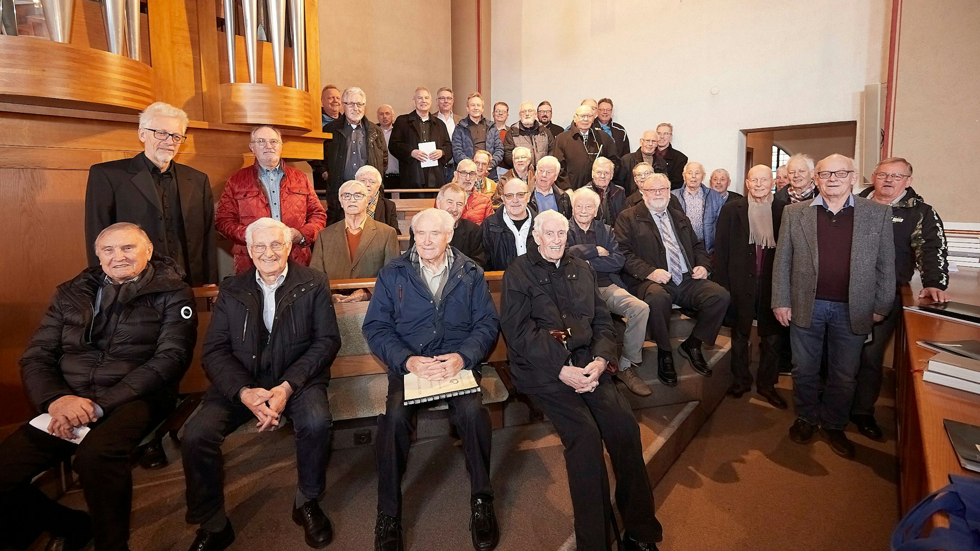 Zahlreiche Sänger von Männergesangvereinen stehen und sitzen an einer Kirchenorgel.