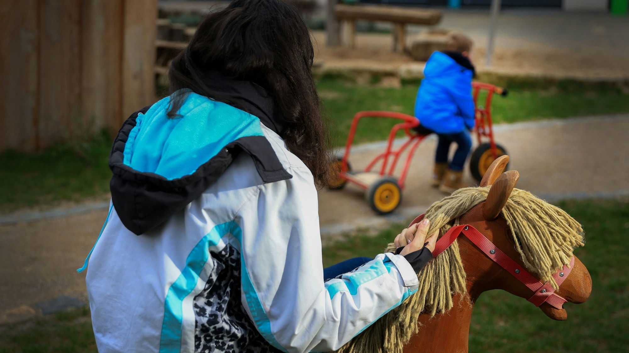 Die alleinerziehende Mutter Valerie H. sitzt auf einem Spielpferd, ihr Sohn ist im Hintergrund zu sehen.