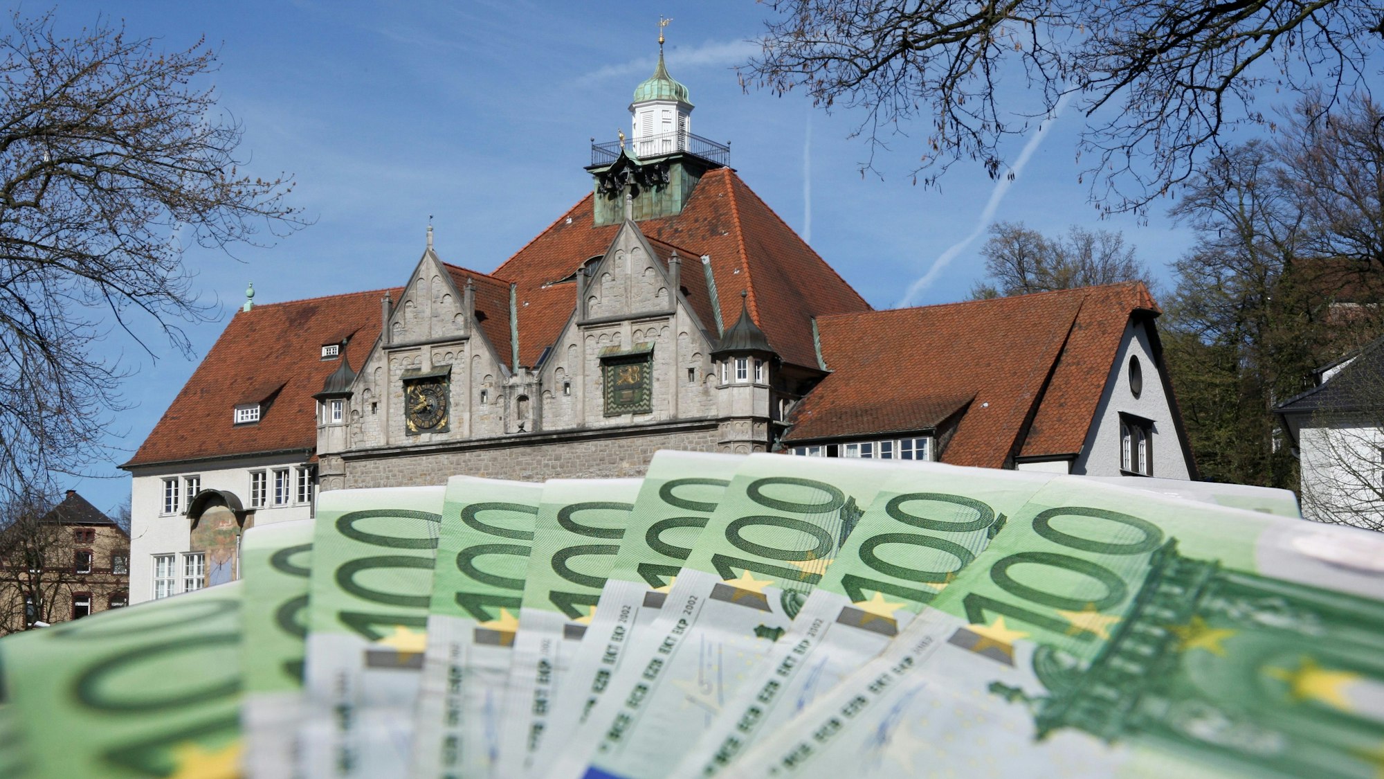 Geldscheine werden aufgefächert vor das Rathaus in Bergisch Gladbach gehalten.