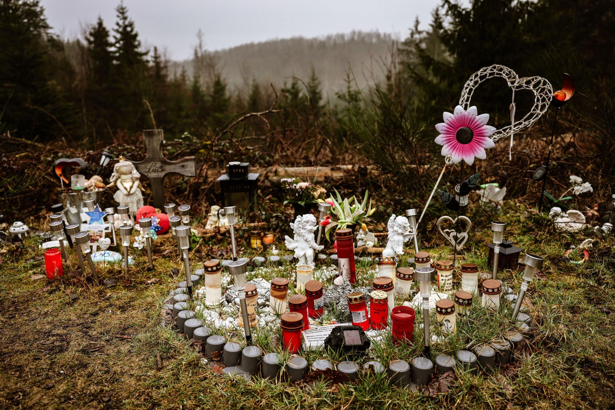 05.03.2024, Nordrhein-Westfalen, Freudenberg: Kerzen, Blumen und Figuren liegen am Fundort an der Landesgrenze zwischen Rheinland-Pfalz und Nordrhein-Westfalen. Die zwölf Jahre alte Schülerin Luise war im März 2023 erstochen worden. Zwei strafunmündige Mädchen hatten die Tat gestanden.