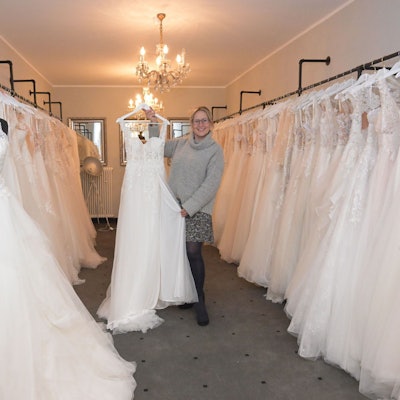 Carolin Amerling hält ein Hochzeitskleid in die Kamera.