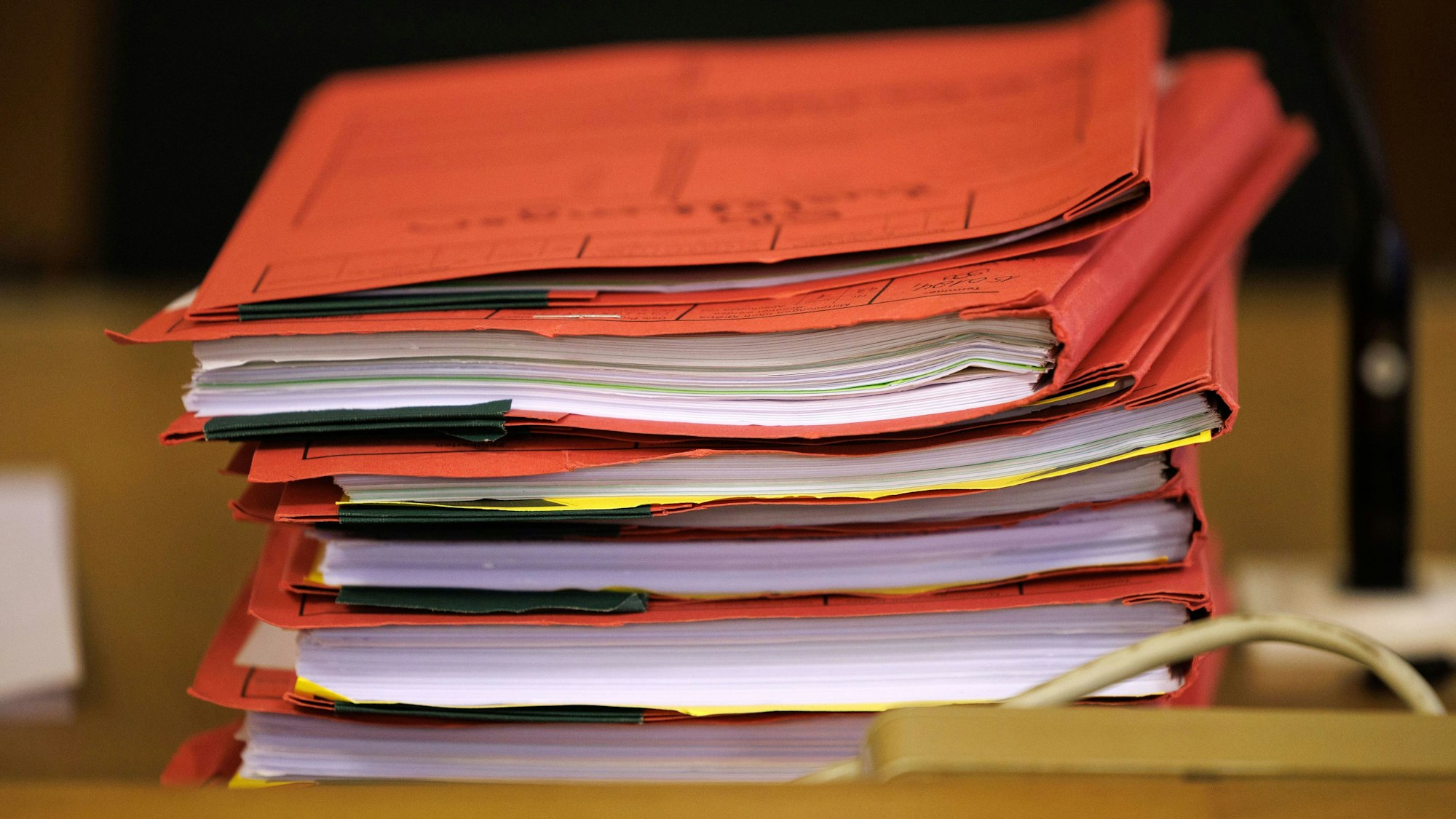Prozessakten liegen in einem Saal an einem Landgericht auf einem Tisch.