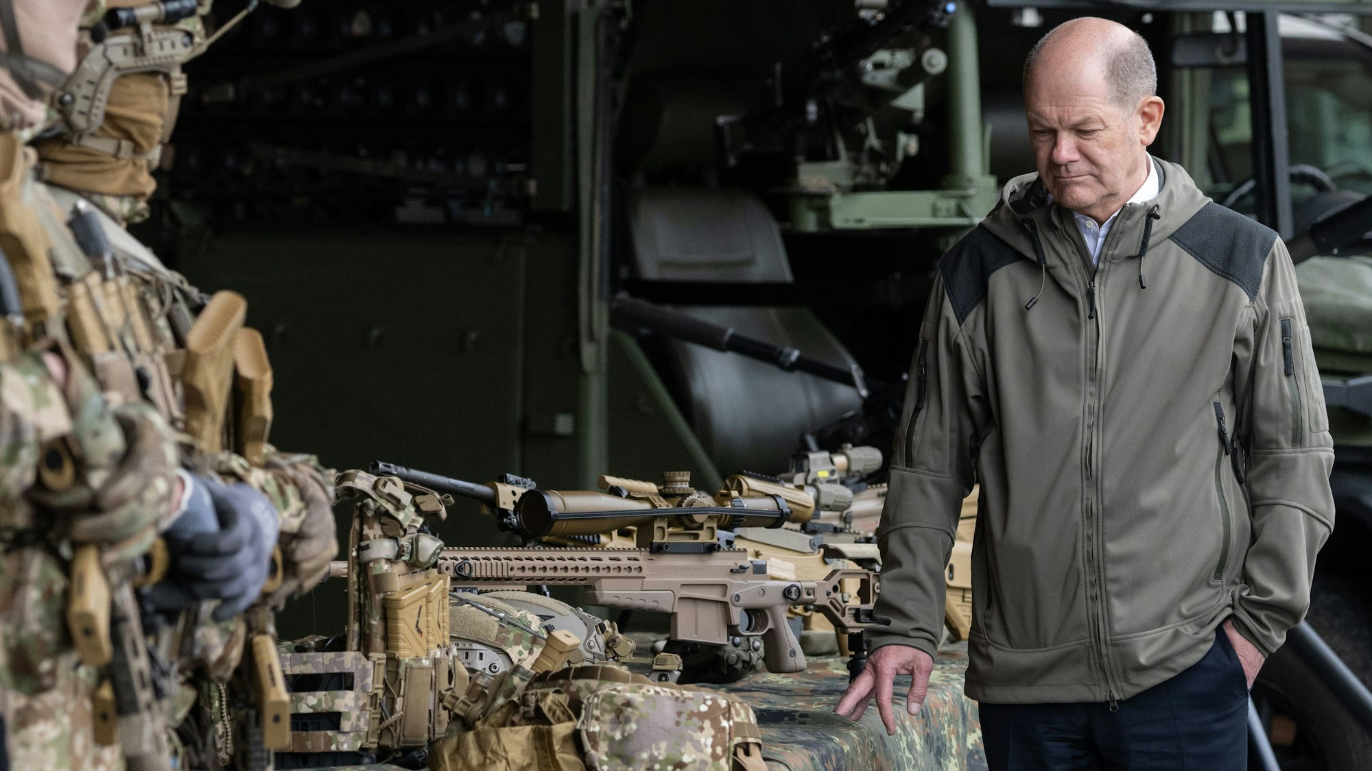 Bundeskanzler Olaf Scholz (SPD) betrachtet während eines Besuchs des Kommandos Spezialkräfte (KSK) der Bundeswehr Waffen. Vor allem aus Großbritannien kommt zuletzt harte Kritik am Kanzler.