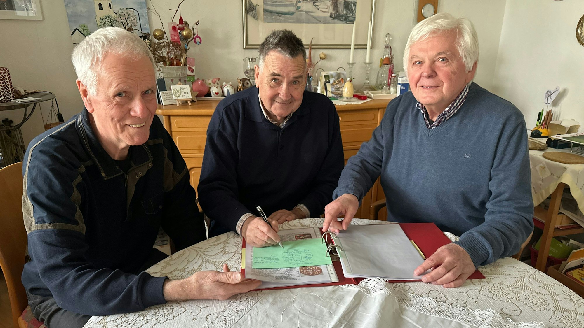 Mitglieder des Vorstandes der Kolpingsfamilie Sankt Augustin blättern in einem Aktenordner, um die Feier zum 100-jährigen Bestehen vorzubereiten. Mit dabei sind Bernd Walterscheid, Kunibert Krenz und Erich Plötz.