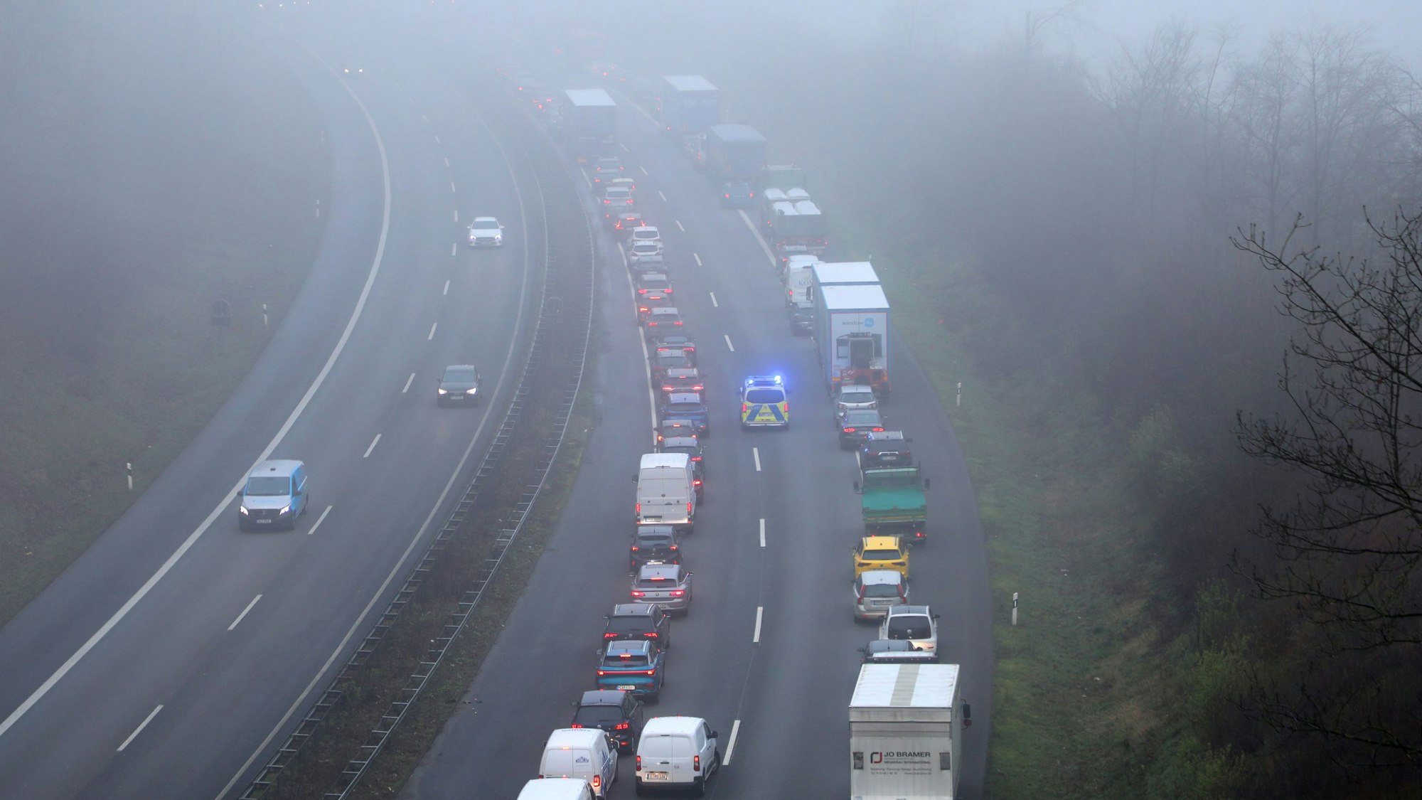 Ein Polizeifahrzeug fährt mit Blaulicht durch eine Rettungsgasse auf der Autobahn 4 zwischen Overath und Untereschbach in Richtung Köln.