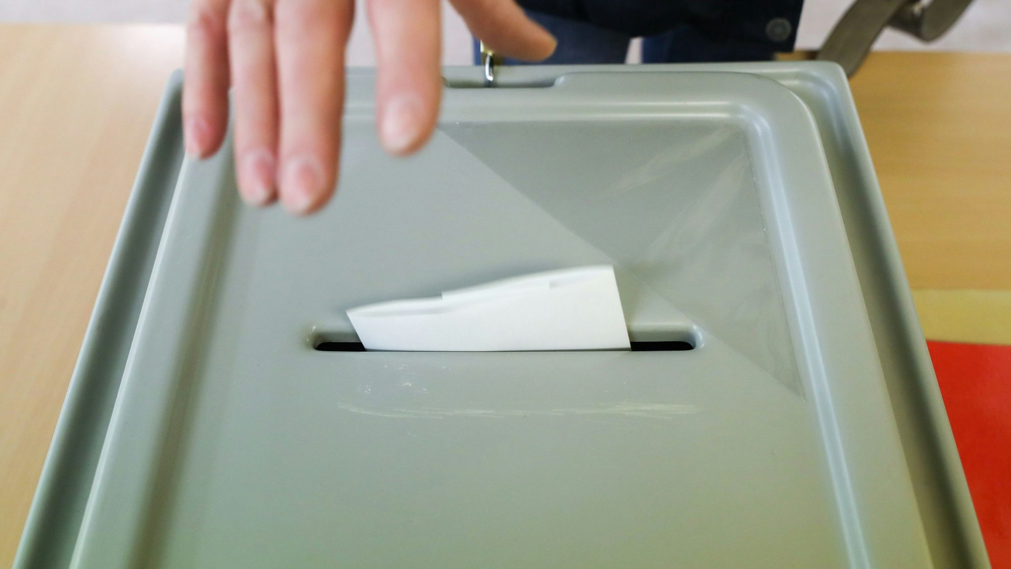 Eine Frau wirft ihren Stimmzettel für die Oberbürgermeisterwahl in die Wahlurne.