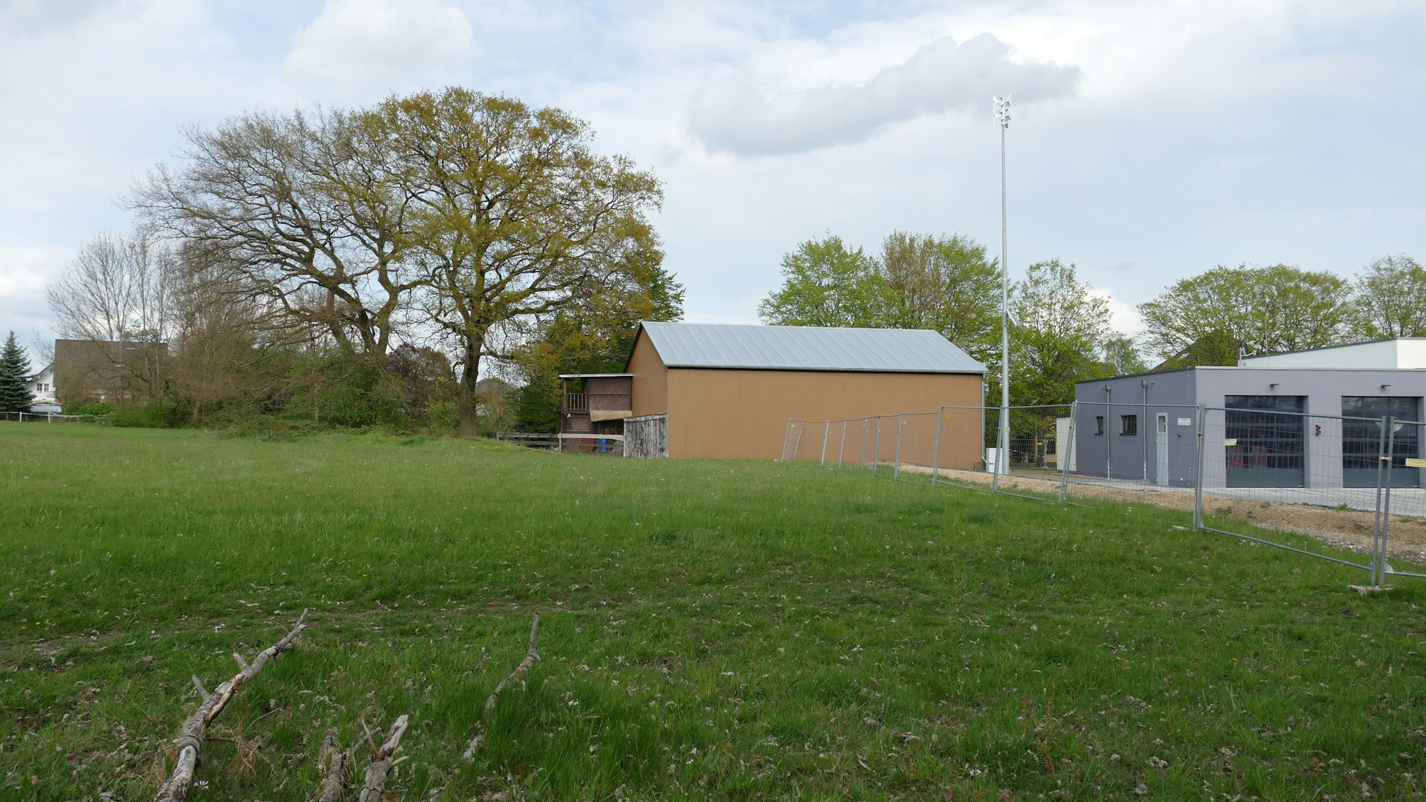 Eine Wiese, im Hintergrund zwei Hallen.