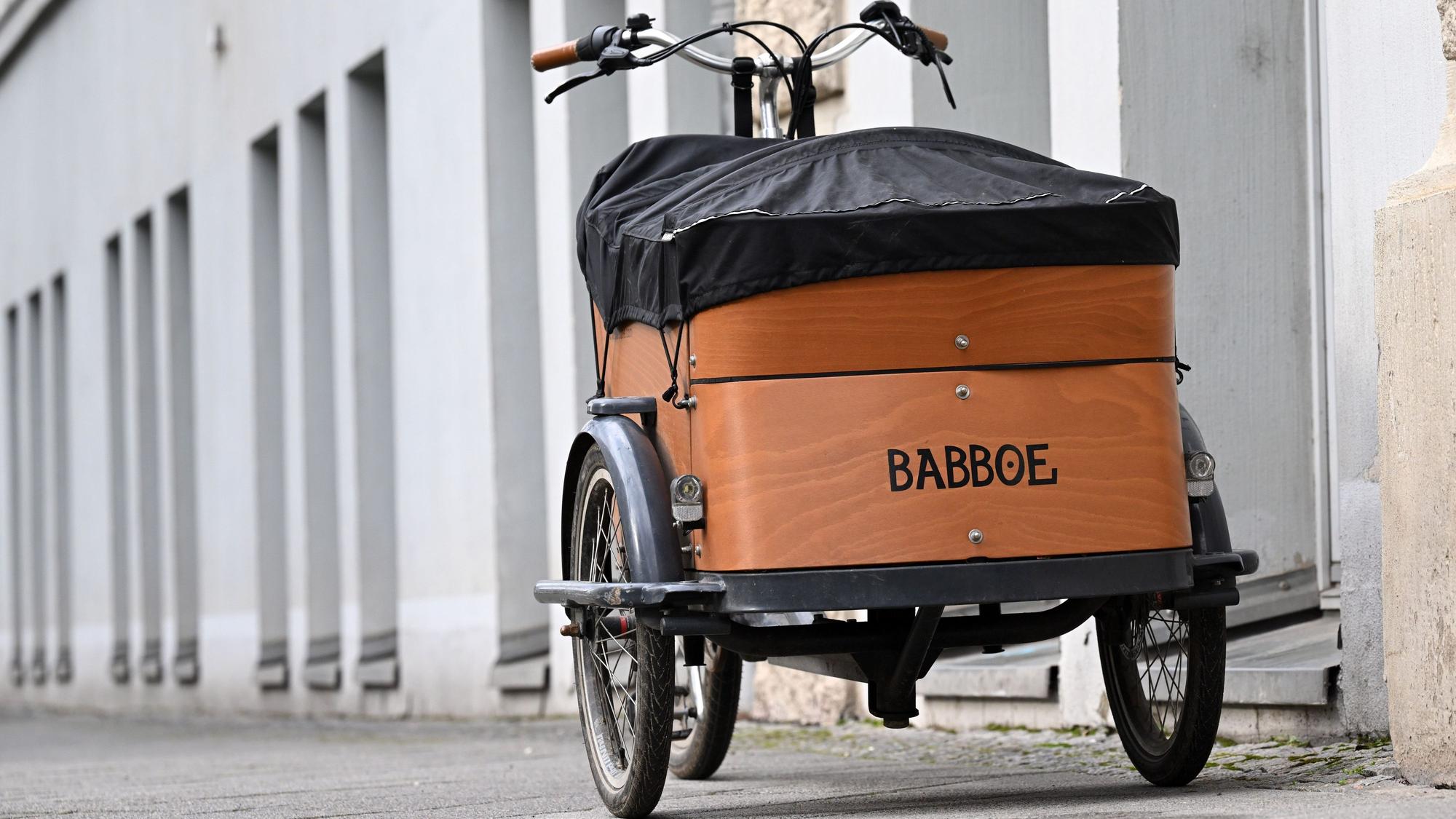 Ein Babboe-Lastenfahrrad parkt auf einem Bürgersteig neben einer Häuserfassade.
