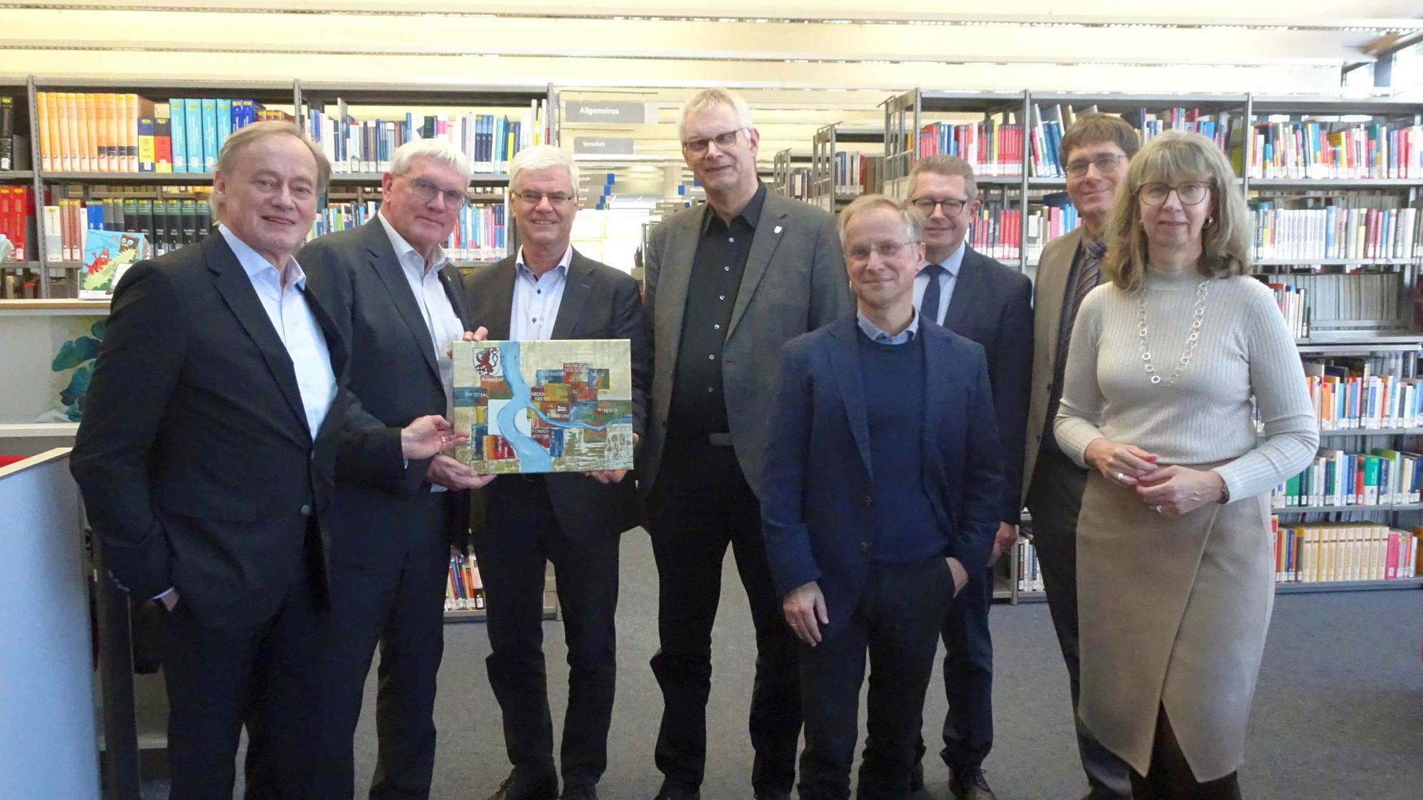 Landrat Sebastian Schuster (2.v.l.) übergab ein Geschenk an Bibliotheksleiter Dr. Armin Ehrhardt (rechts daneben) im Beisein von Kanzlerin Angela Fischer (rechts) Präsident Hartmut Ihne (l.), Bürgermeister Ludger Banken (4.v.l.), Hans Dieter Wirtz (3.v.r.) und die Dekane Richard Jäger (4.v.r.) und Peter Muck (2.v.r.).