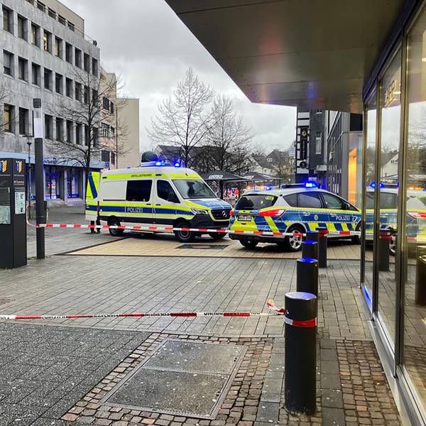 Zwei Polizeiautos stehen vor einem Bankgeschäft. Davor ist ein Tatport mit Flatterband abgesperrt worden.