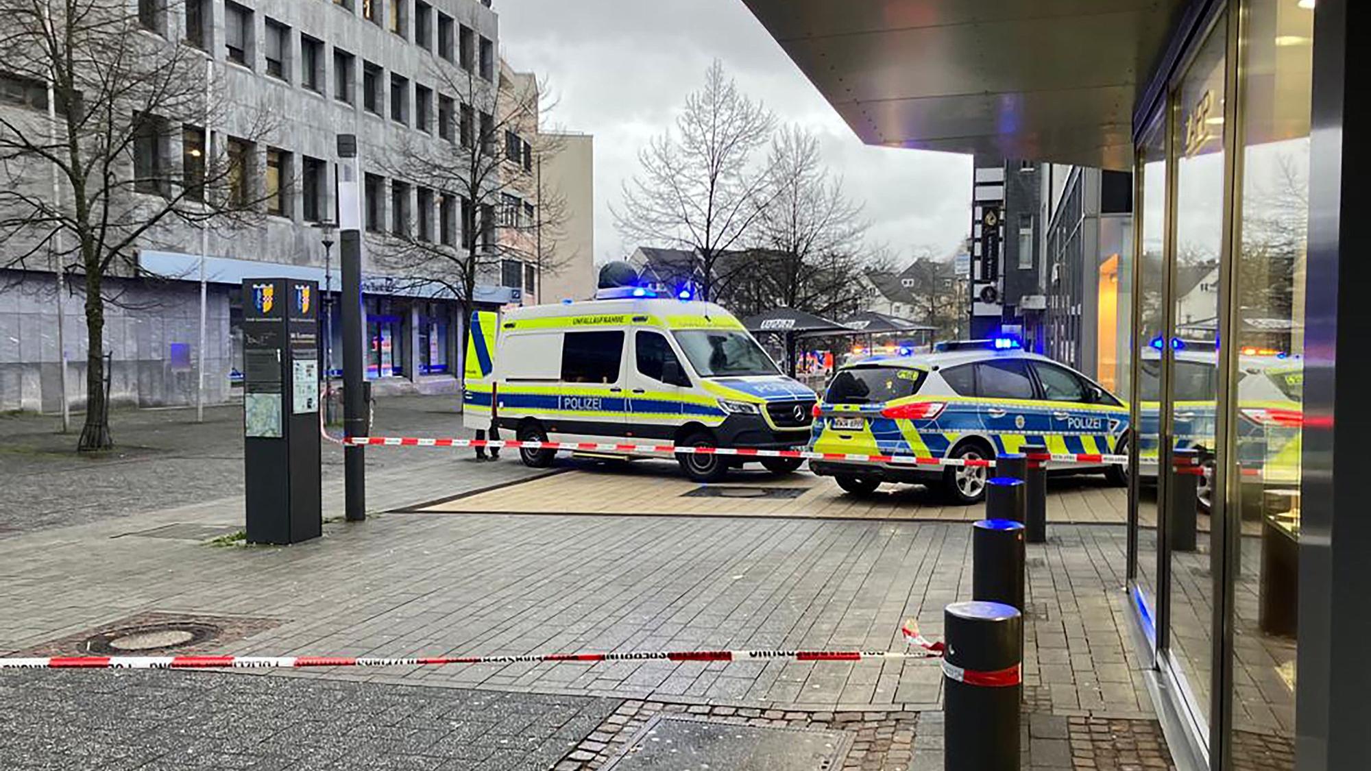 Zwei Polizeiautos stehen vor einem Bankgeschäft. Davor ist ein Tatport mit Flatterband abgesperrt worden.
