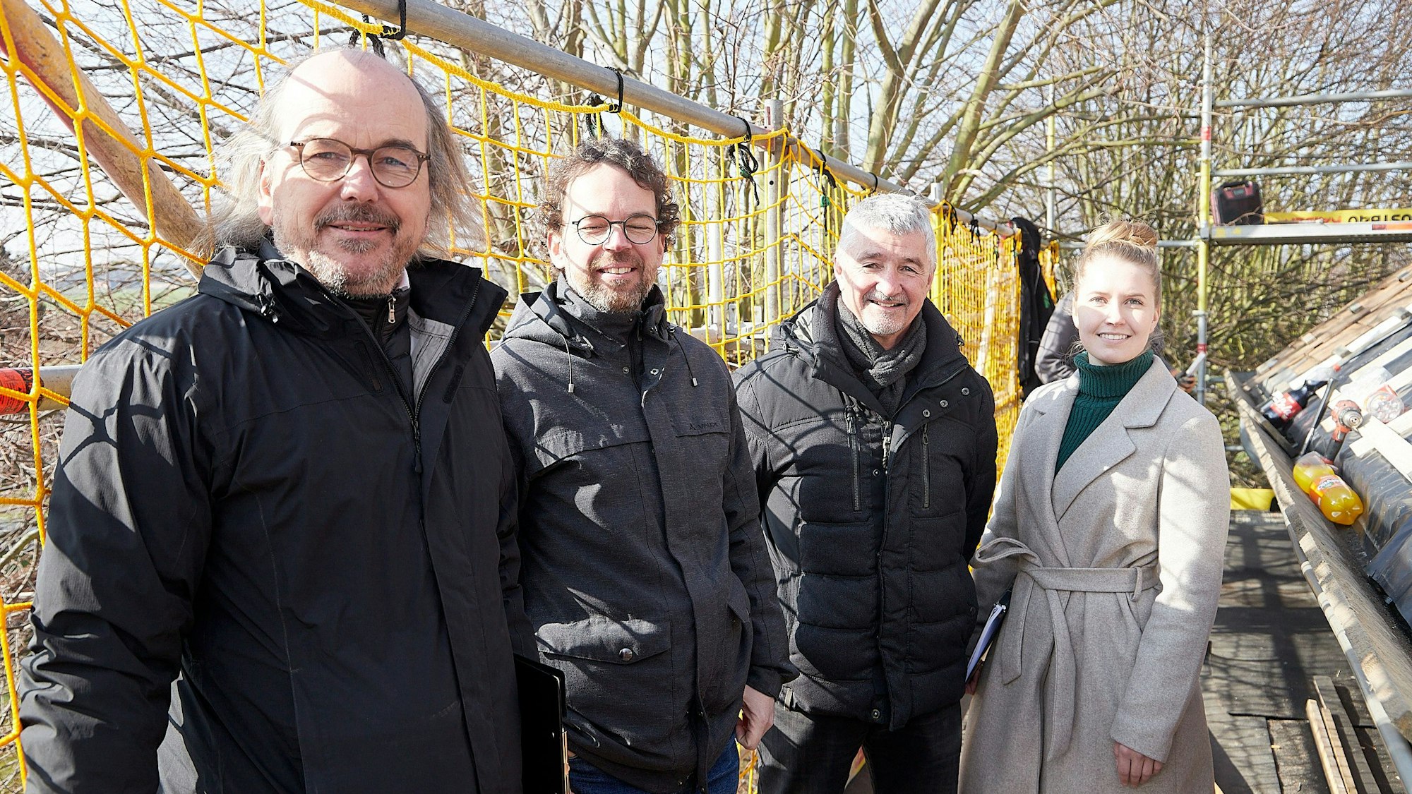 Drei Männer und eine Frau stehen im Freien an der Baustelle der Kirche in Holzheim.