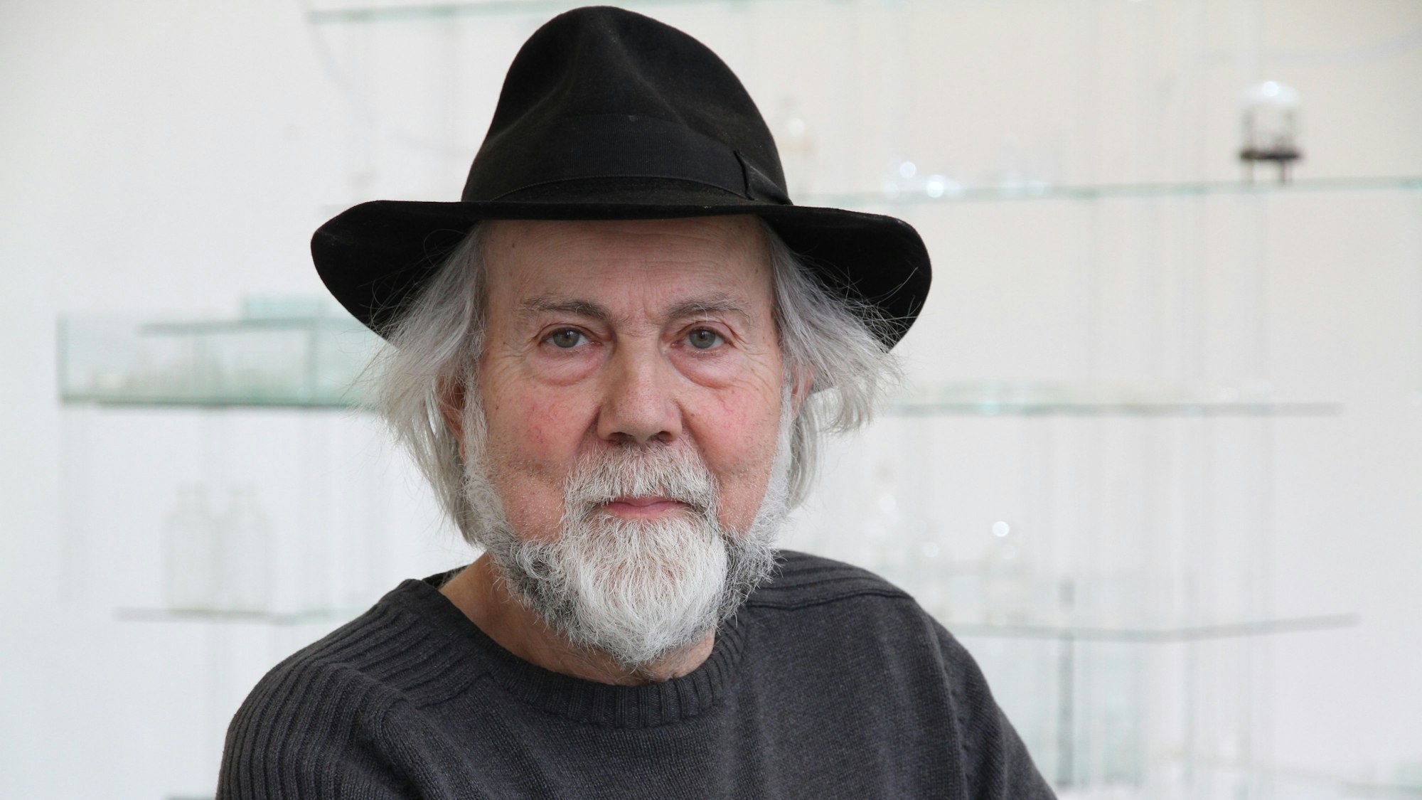 Ein Mann mit einem schwarzen Hut und einem grauen Pullover