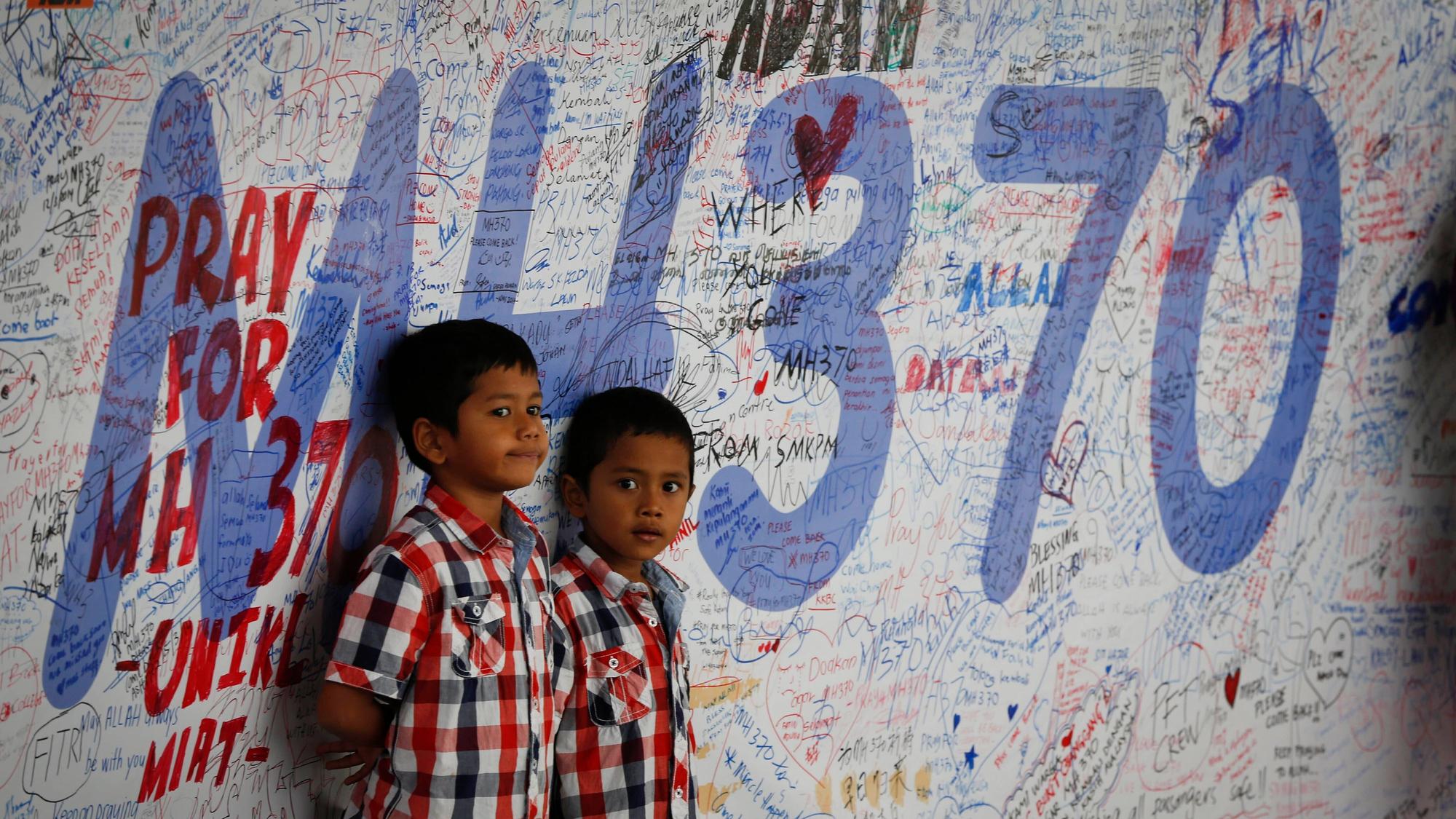 Zwei kleine Kindern stehen an einer Gedenktafel für Angehörige des Flugs MH370 in Sepang, Malaysia