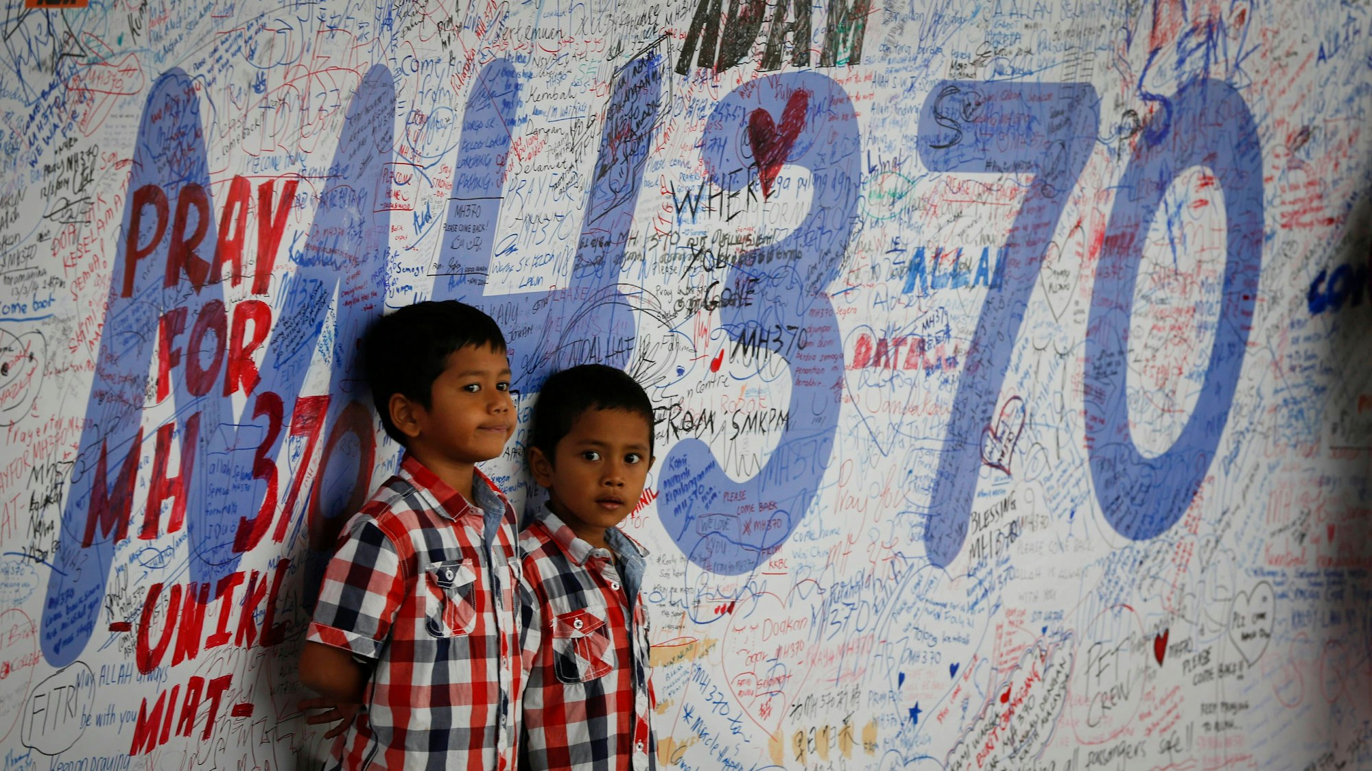 Zwei kleine Kindern stehen an einer Gedenktafel für Angehörige des Flugs MH370 in  Sepang, Malaysia