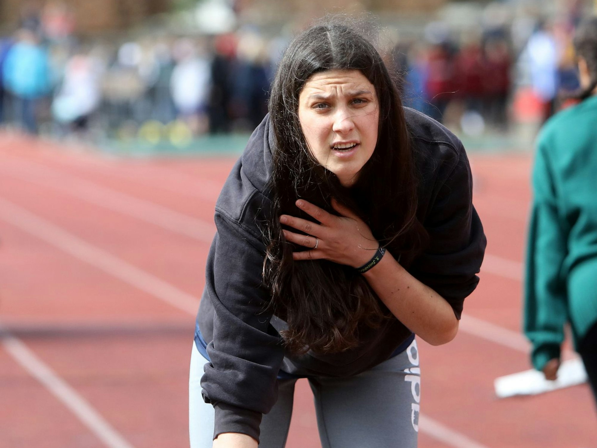 Eine dunkelhaarige Frau steht auf einer Laufbahn.