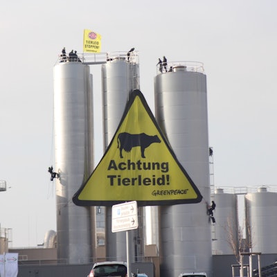 Aktivisten seilen sich an den Silos ab und breiten ein großes Banner mit der Aufschrift „Achtung Tierleid“ aus.
