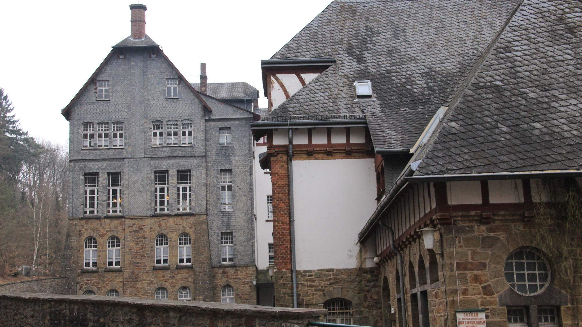 Ein großes, verschachteltes Gebäude aus Bruchstein, Fachwerk und Schiefer.