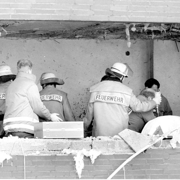 Das Bild zeigt Einsatzkräfte, de sich kurz nach dem Amoklauf um einen Verletzten im Gerichtssaal kümmern. In der Fassade klafft ein großes Loch.