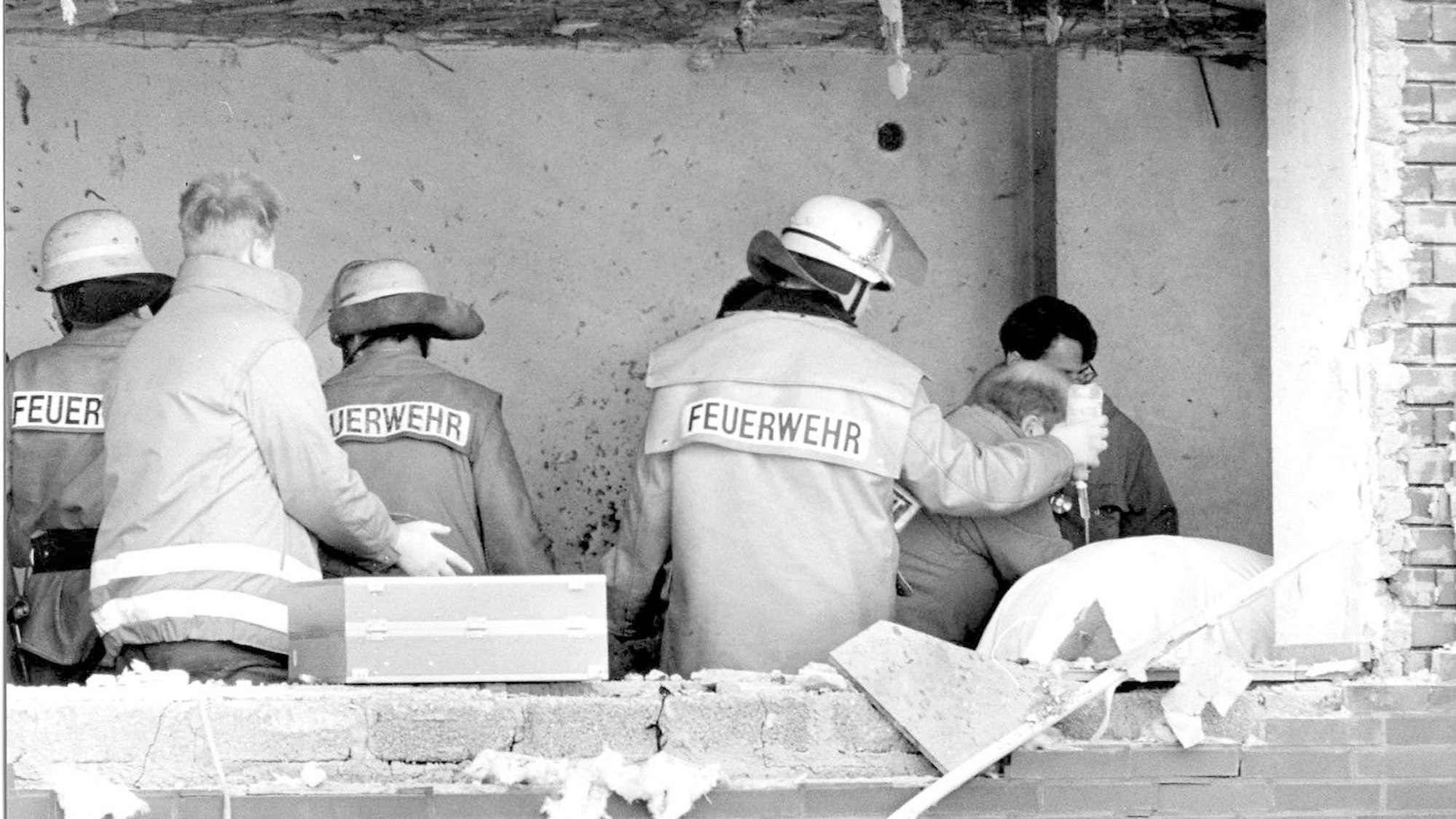 Das Bild zeigt Einsatzkräfte, de sich kurz nach dem Amoklauf um einen Verletzten im Gerichtssaal kümmern. In der Fassade klafft ein großes Loch.