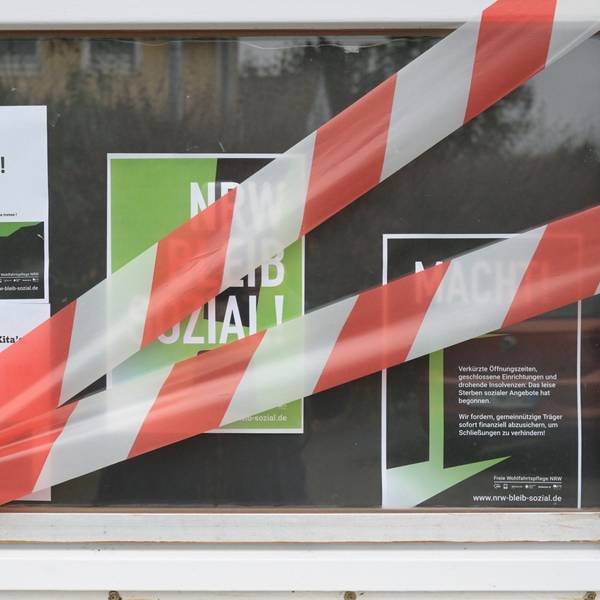 Auf dem Fenster einer Kita kleben Protestplakate und rot-weißes Absperrband.